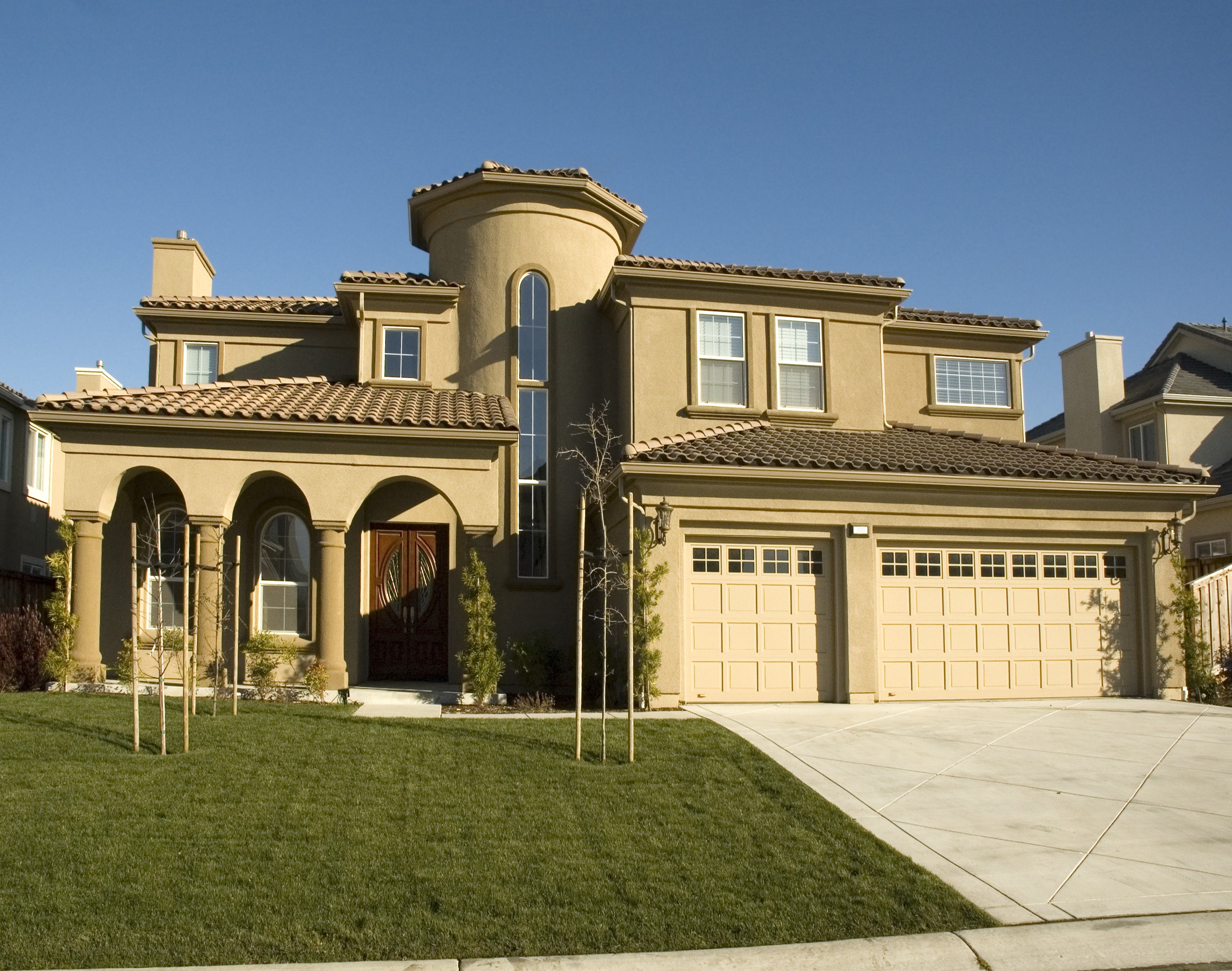 Large stucco house with arched entryway and garage HD Wallpaper