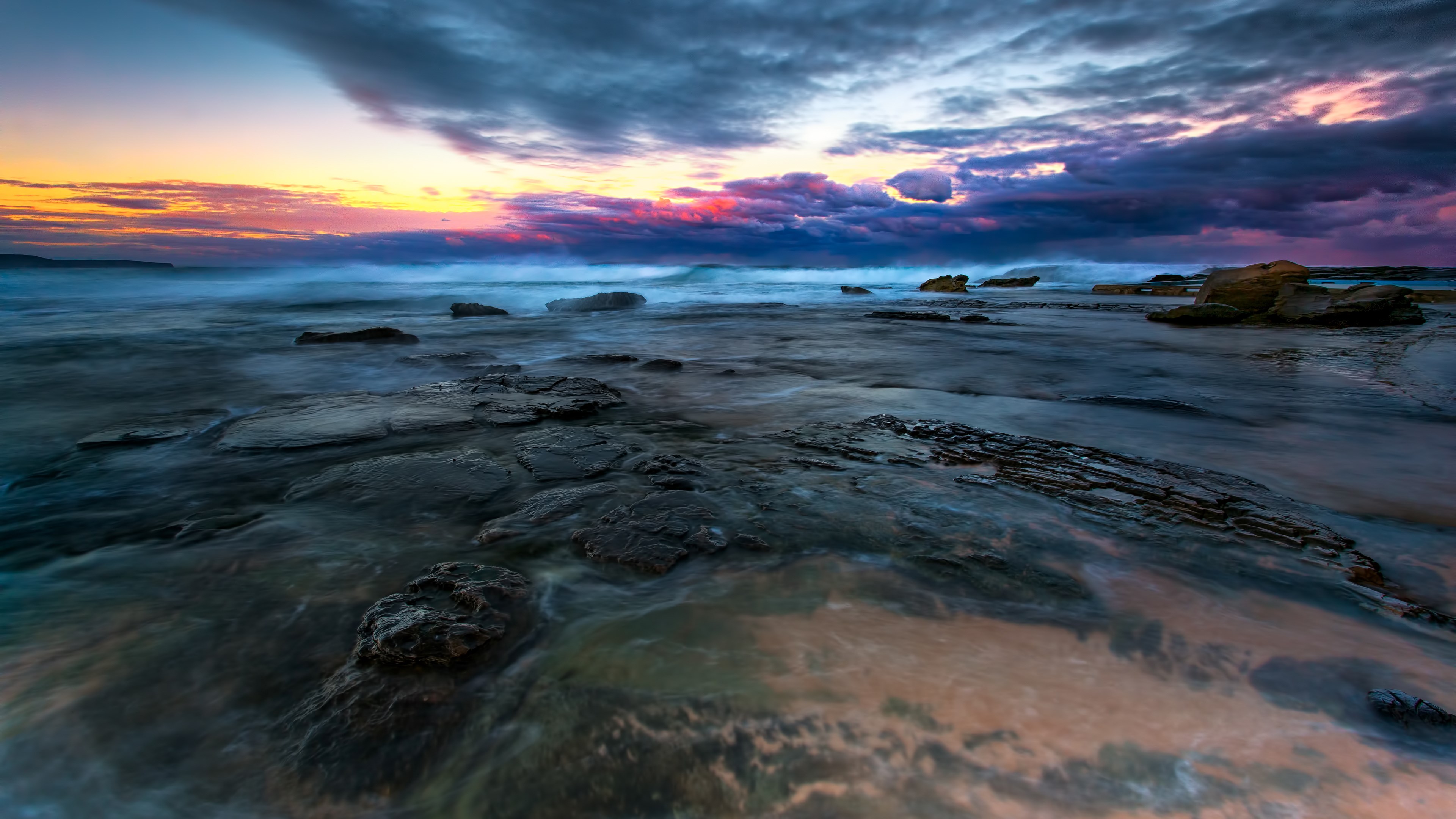Ocean waves crashing on rocky shore at sunset HD Wallpaper