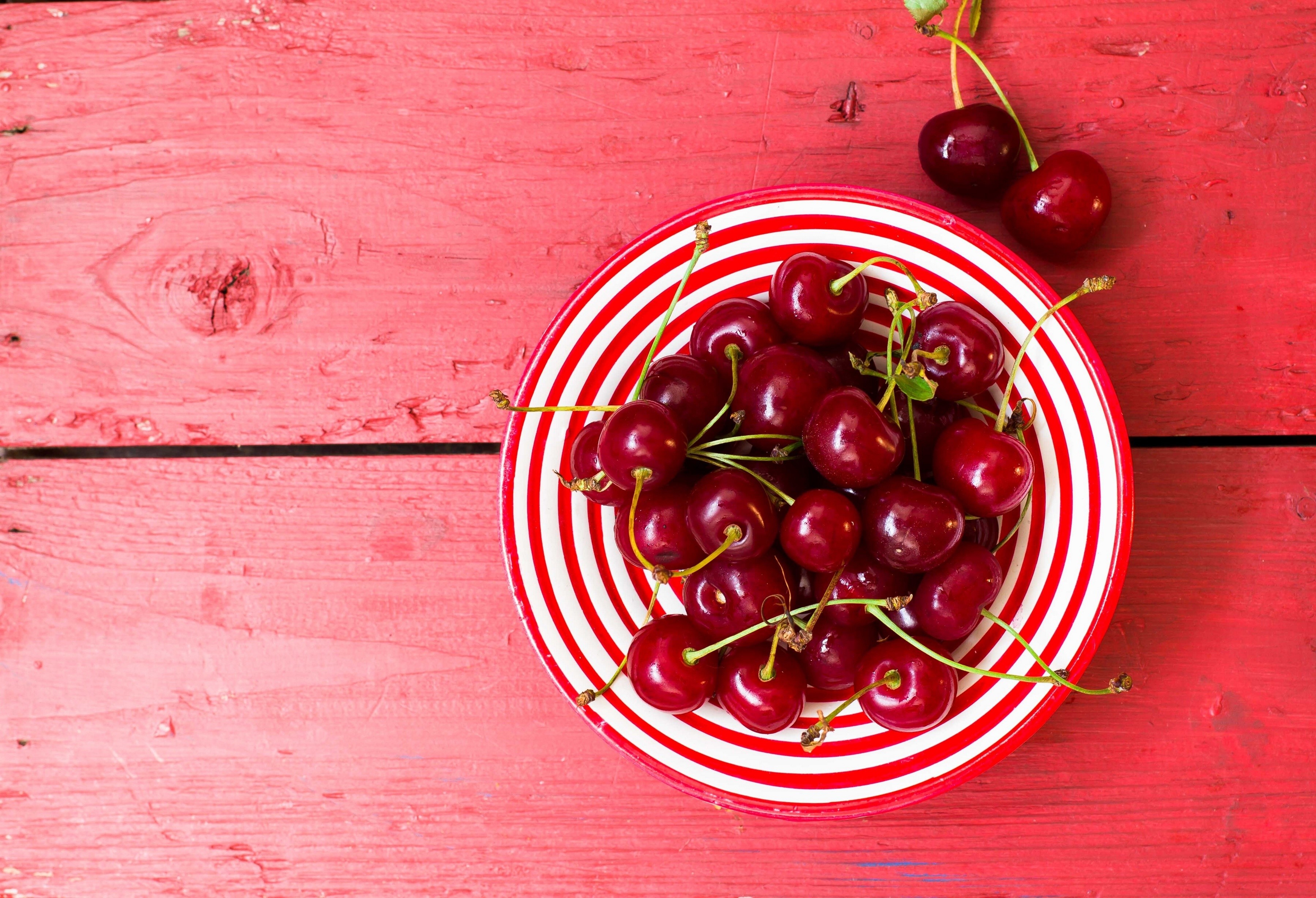 Cherries in a striped bowl on a red wooden table HD Wallpaper
