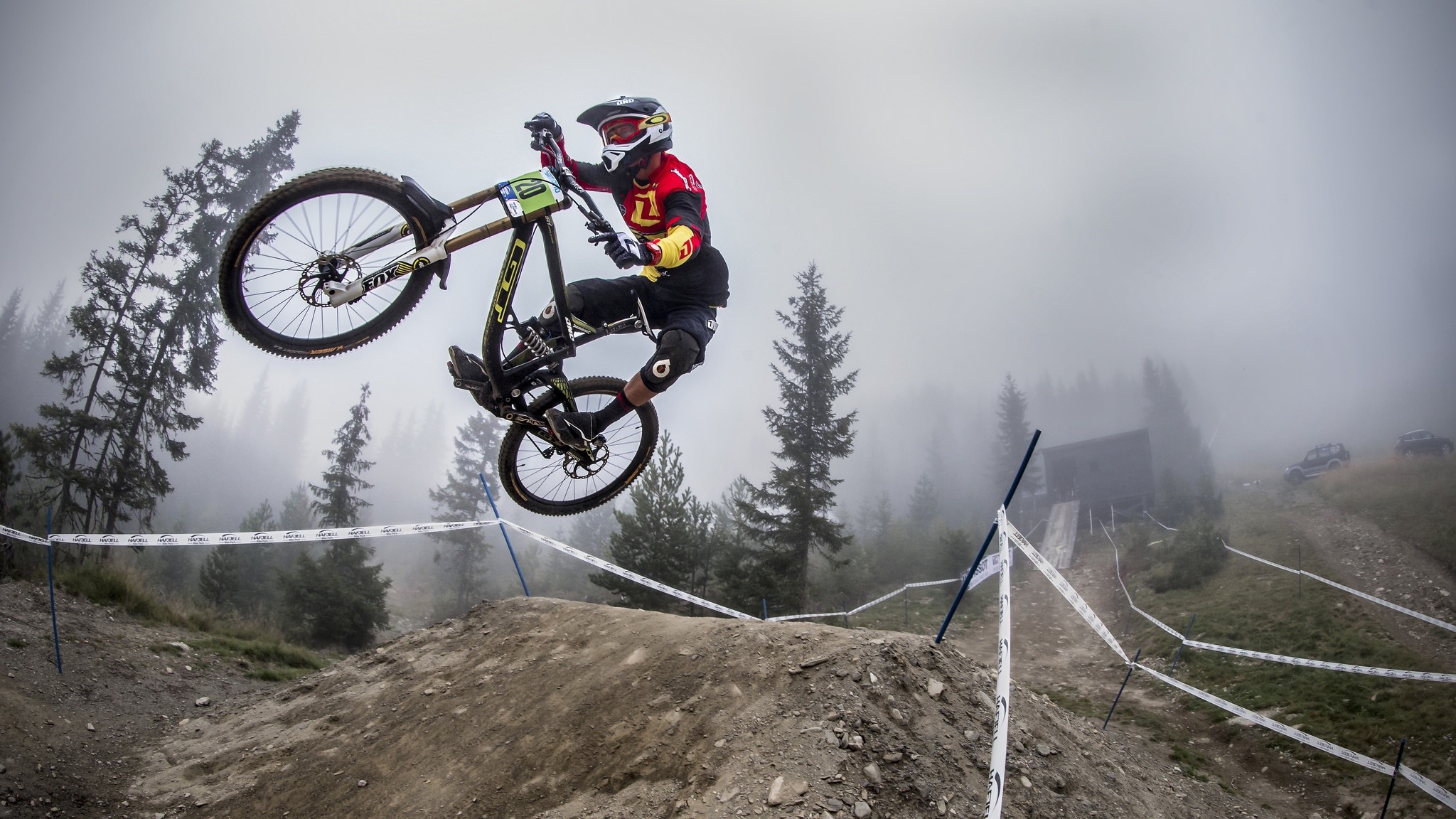 Man performing a bicycle jump in a foggy forest HD Wallpaper