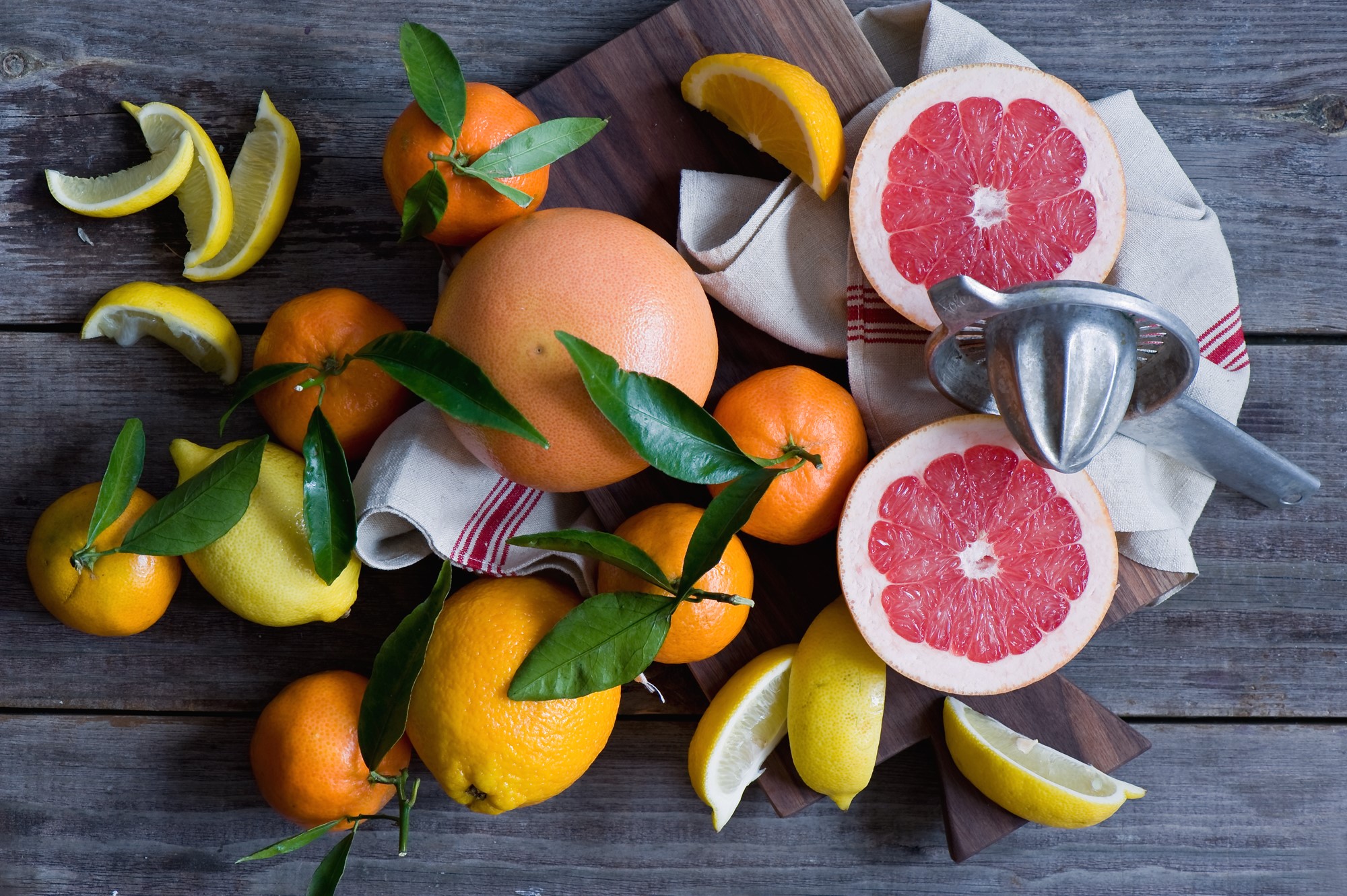 Grapefruits, oranges, lemons, and a juicer on a wooden table HD Wallpaper