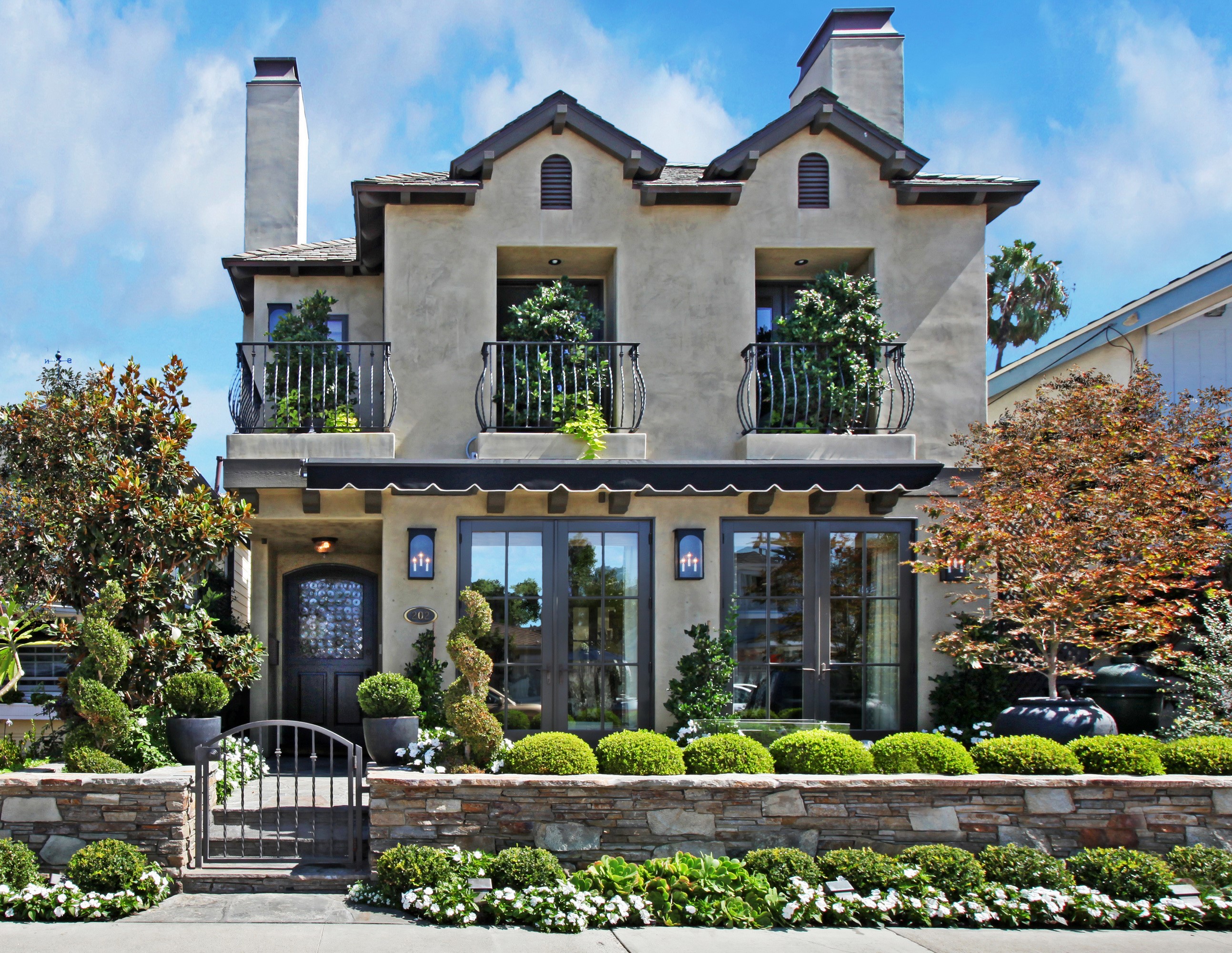 Two-story stucco house with balconies and manicured garden HD Wallpaper
