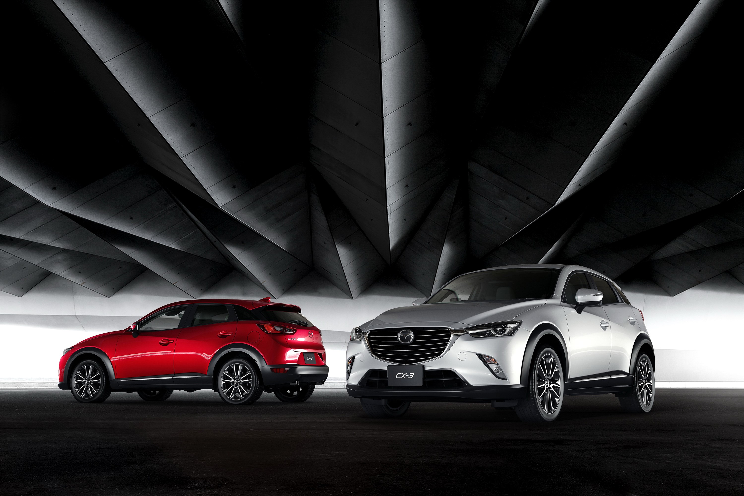 Two Mazda CX-3 cars in a modern architectural setting HD Wallpaper