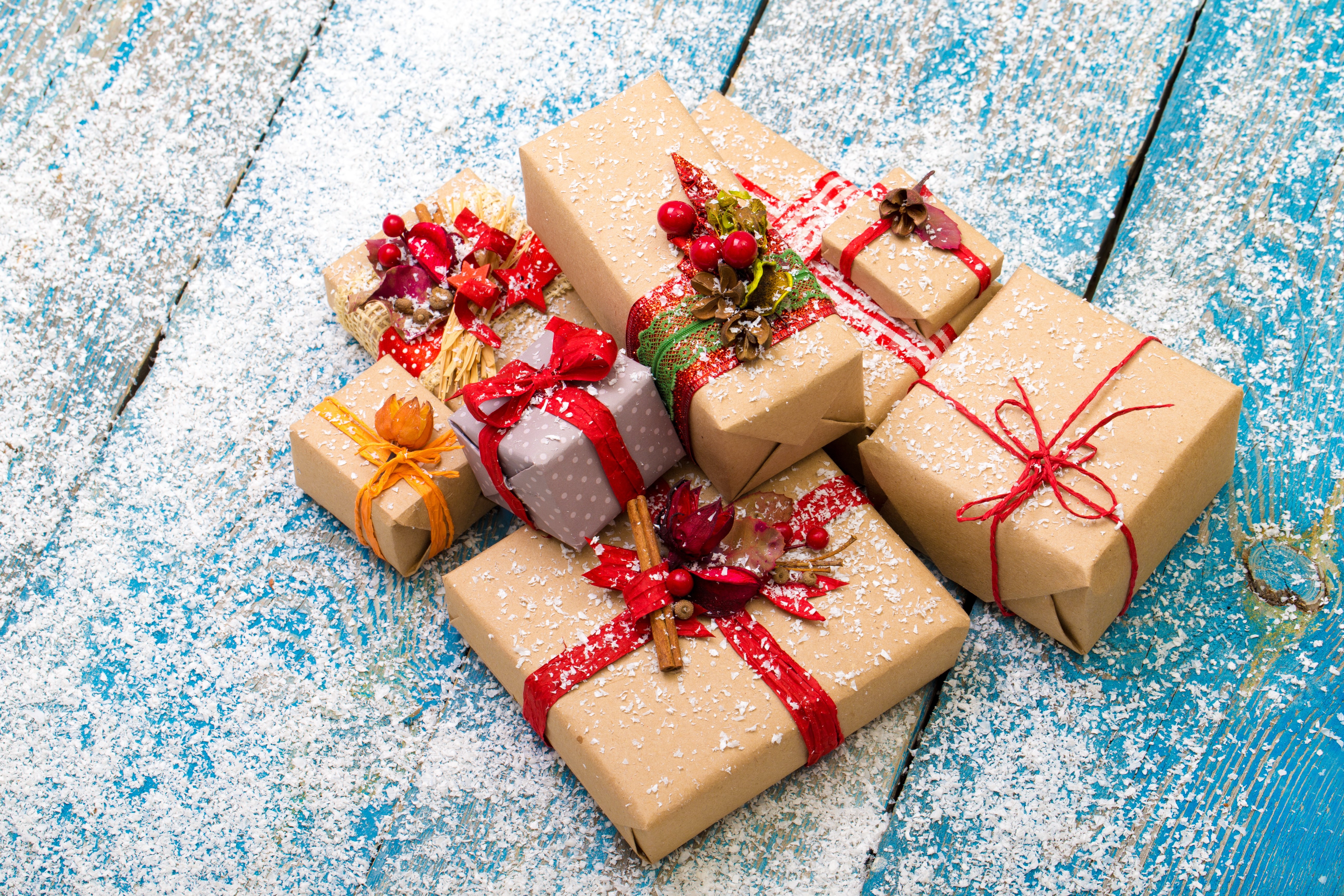 Christmas gifts wrapped in brown paper and tied with red ribbon, dusted with snow HD Wallpaper