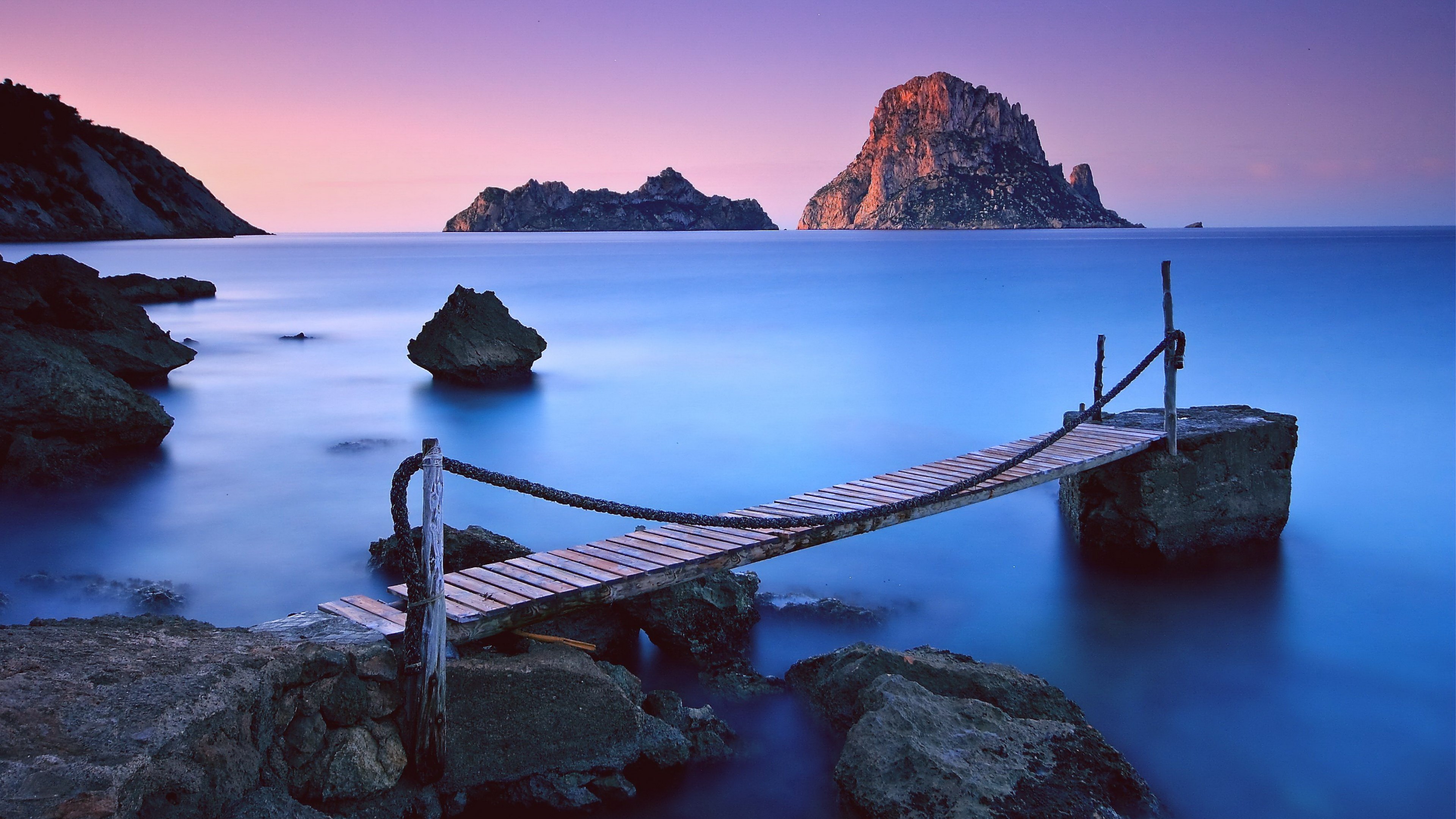 Wooden pier extending into the ocean at sunset HD Wallpaper