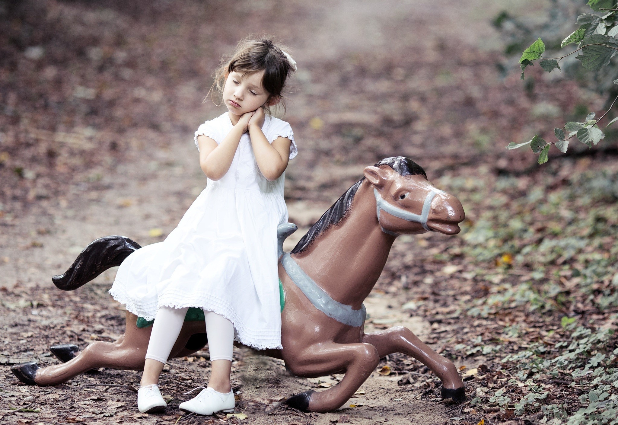 Girl on a toy horse in a forest HD Wallpaper