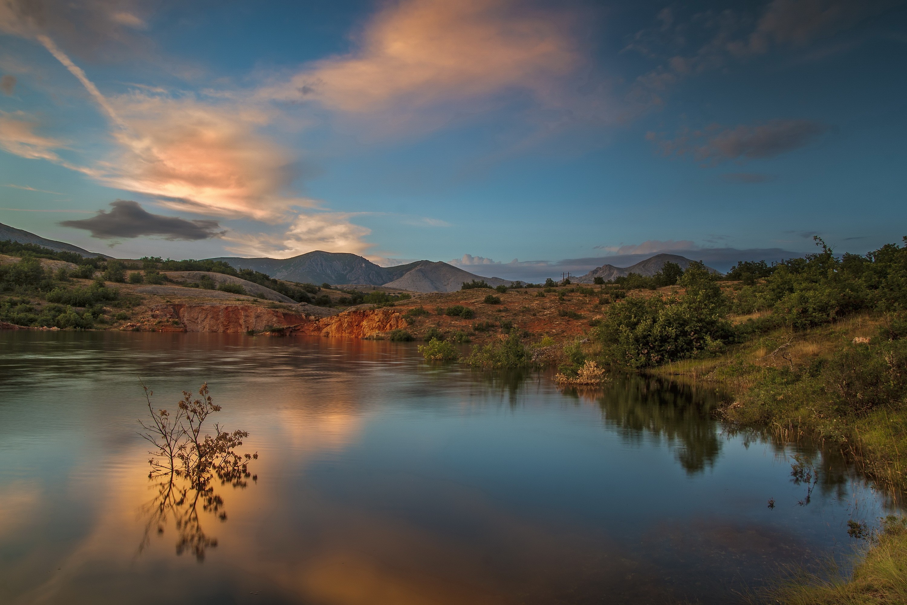 Sunset over a calm lake with hills and clouds HD Wallpaper