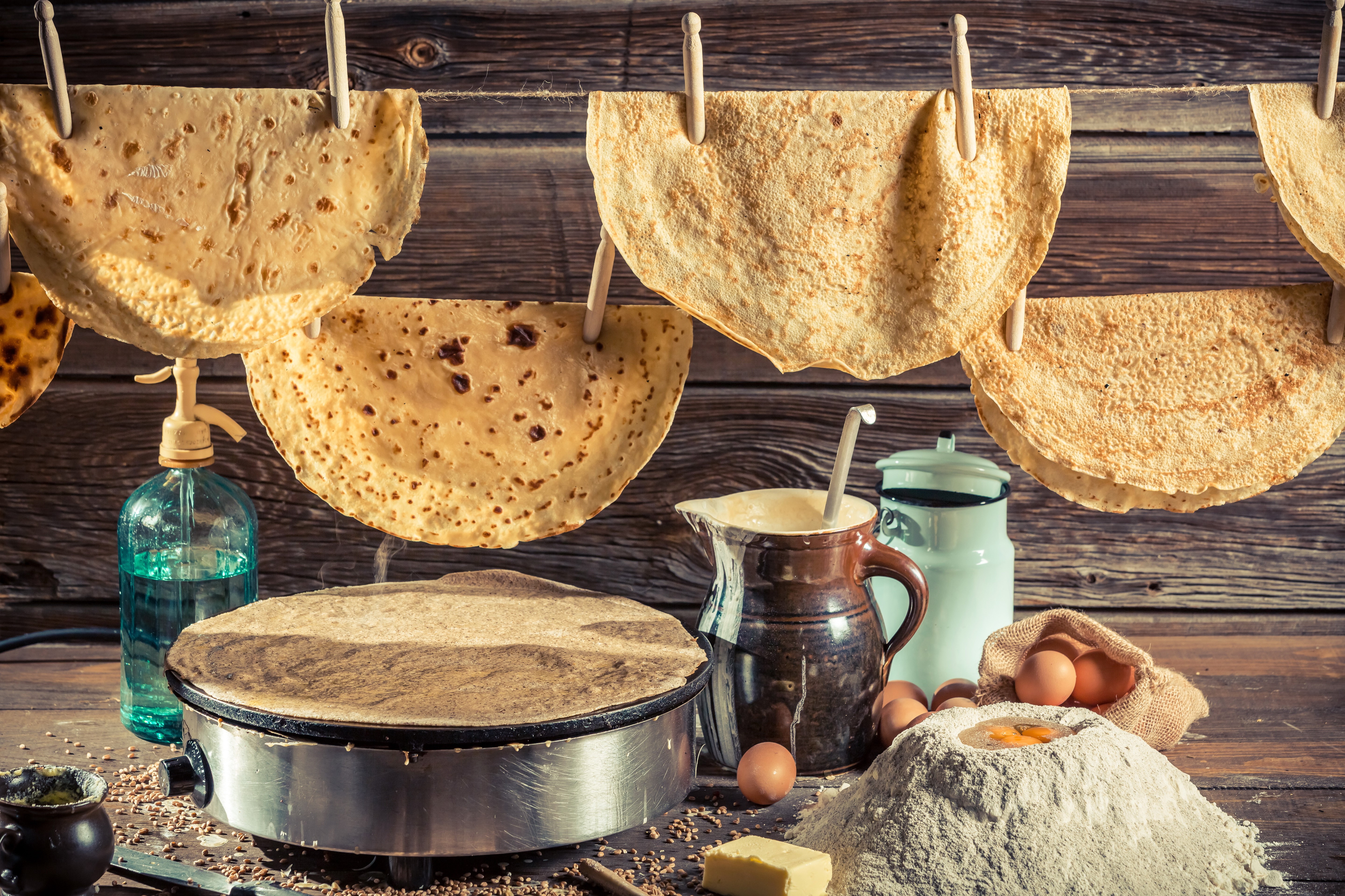 Pancakes drying on a clothesline with cooking ingredients HD Wallpaper