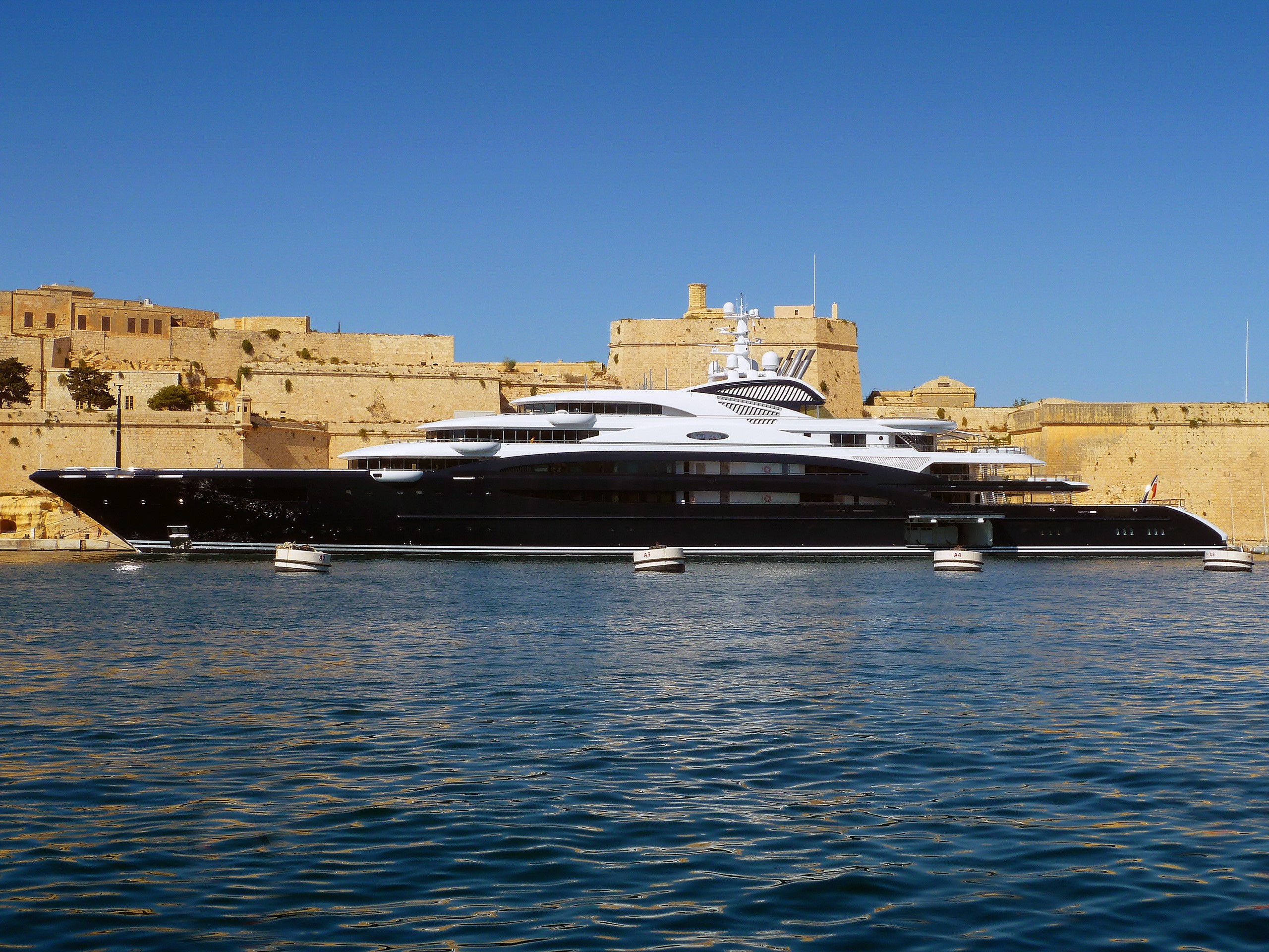 Luxury yacht docked near ancient stone fortifications HD Wallpaper