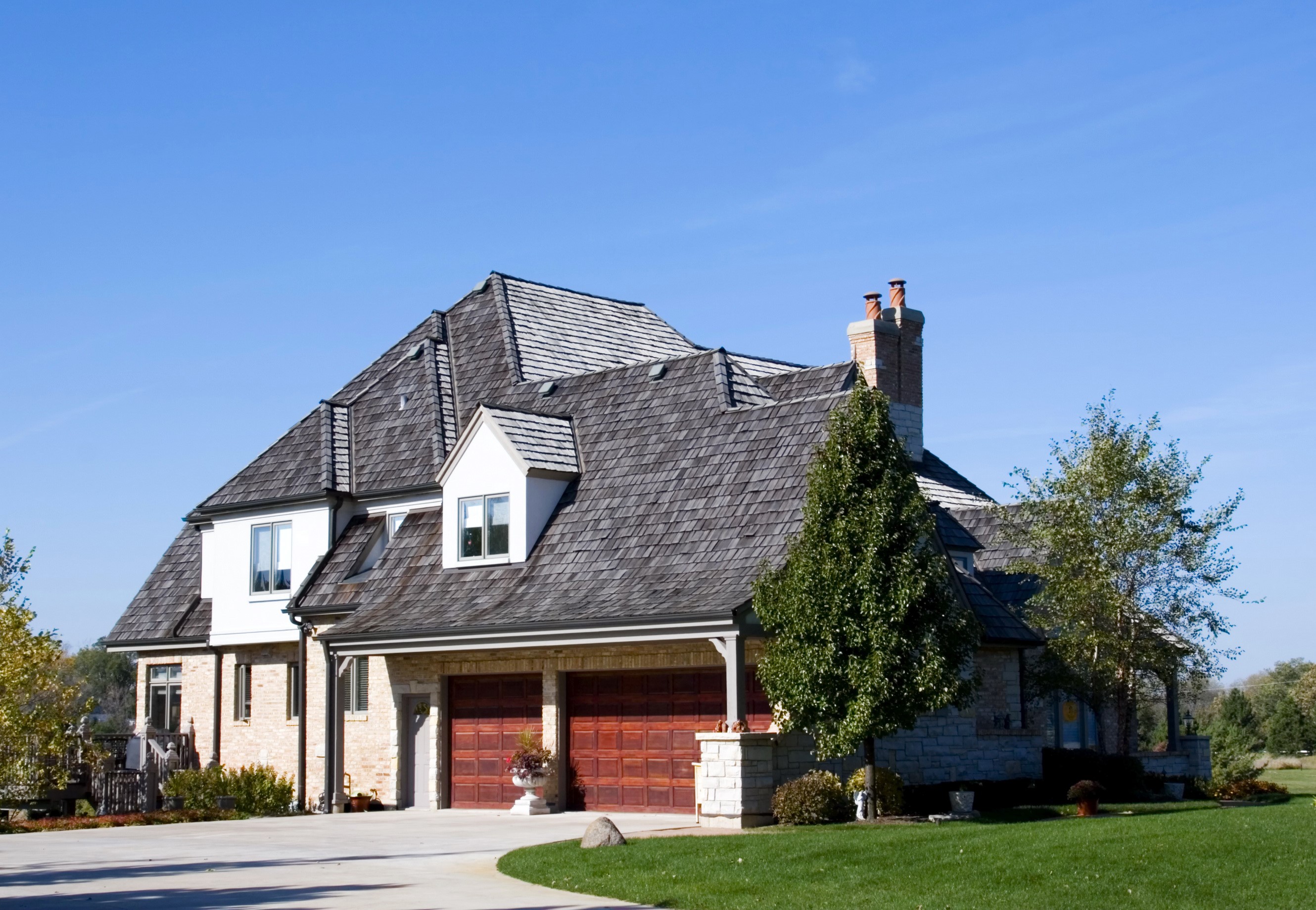 Large stone and brick house with wooden garage doors HD Wallpaper