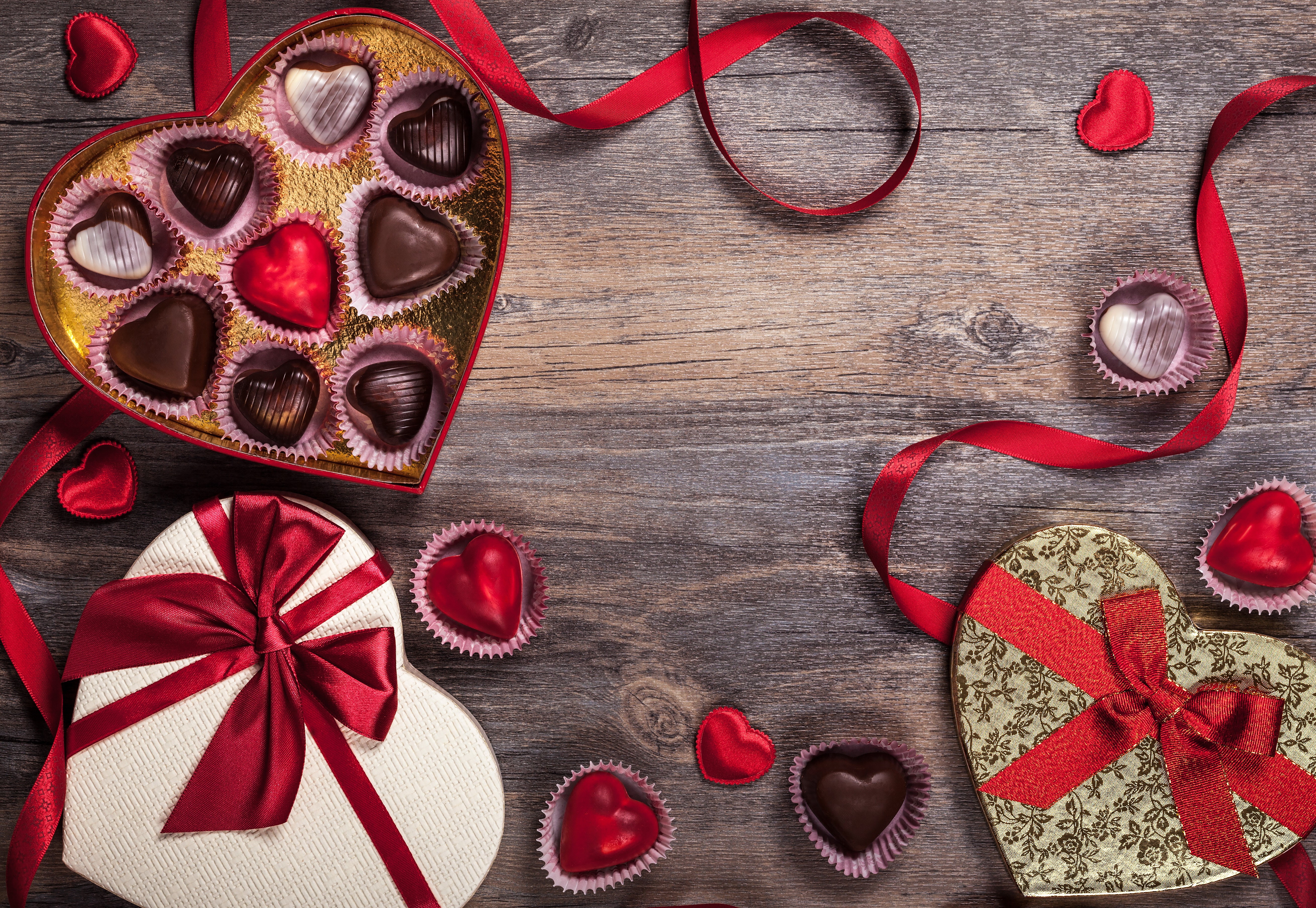Heart-shaped chocolate boxes and red ribbons on wooden background HD Wallpaper