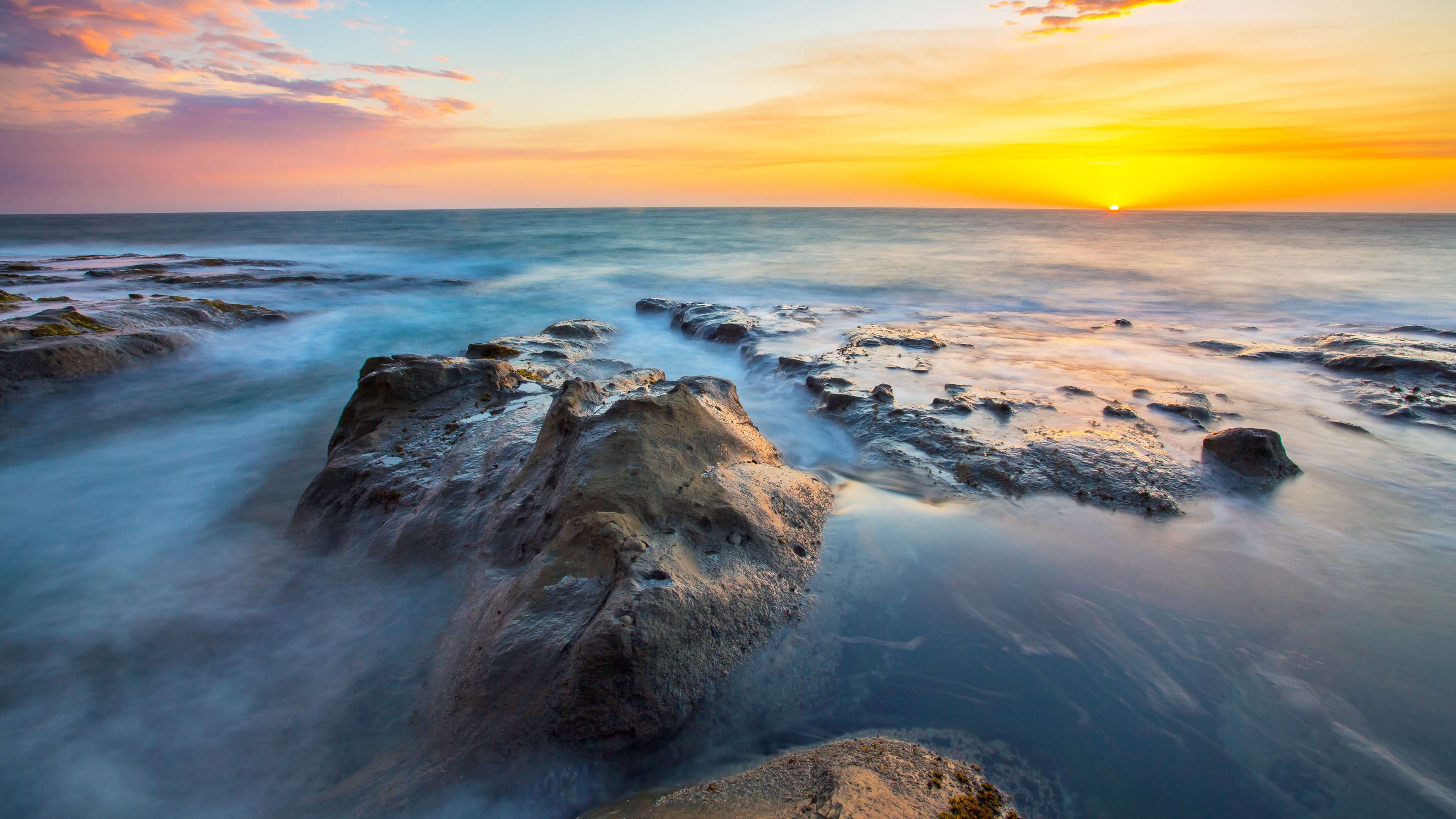 Ocean waves crashing on rocky shore at sunset HD Wallpaper