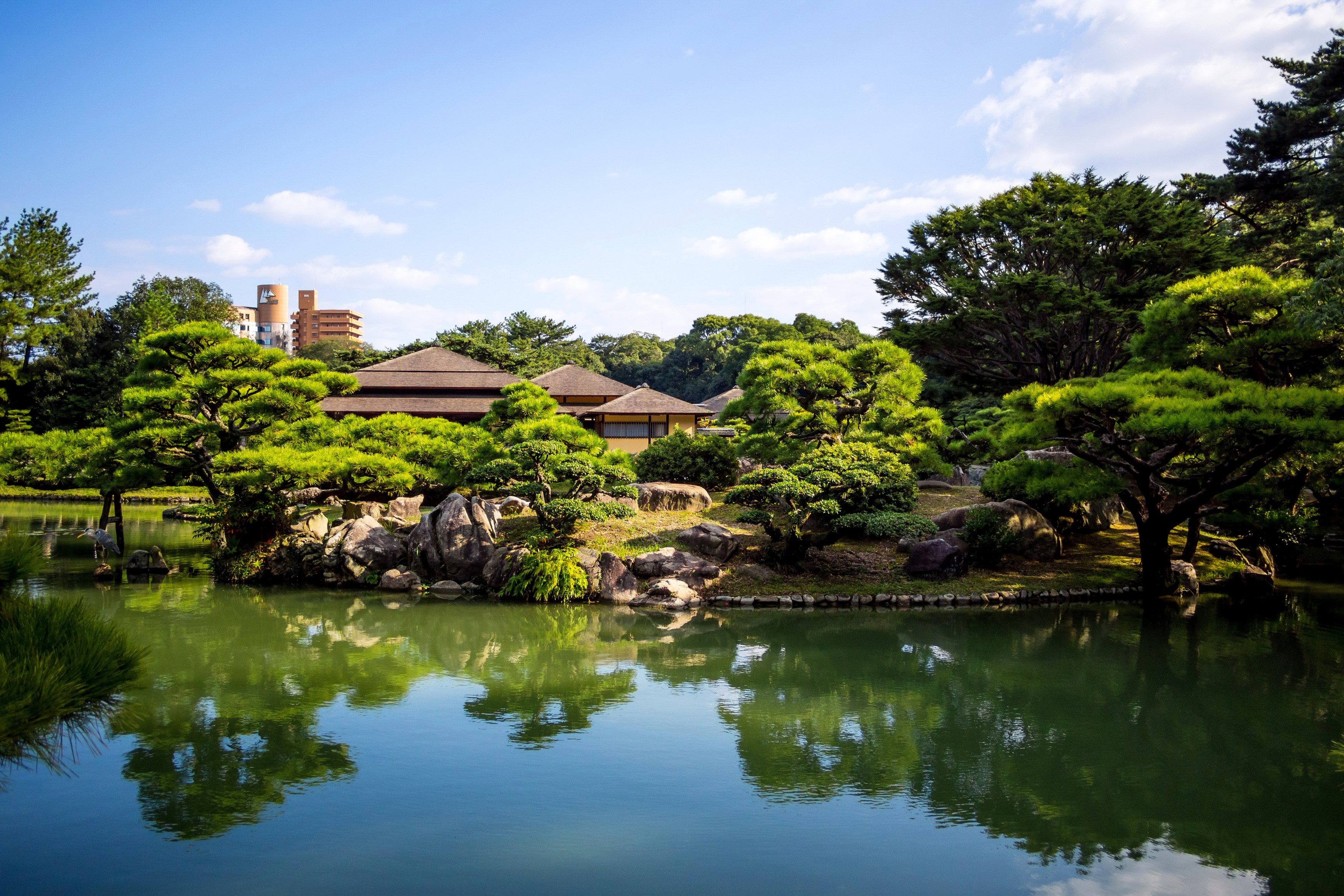 Ritsurin Garden pond with traditional Japanese buildings and trees HD Wallpaper