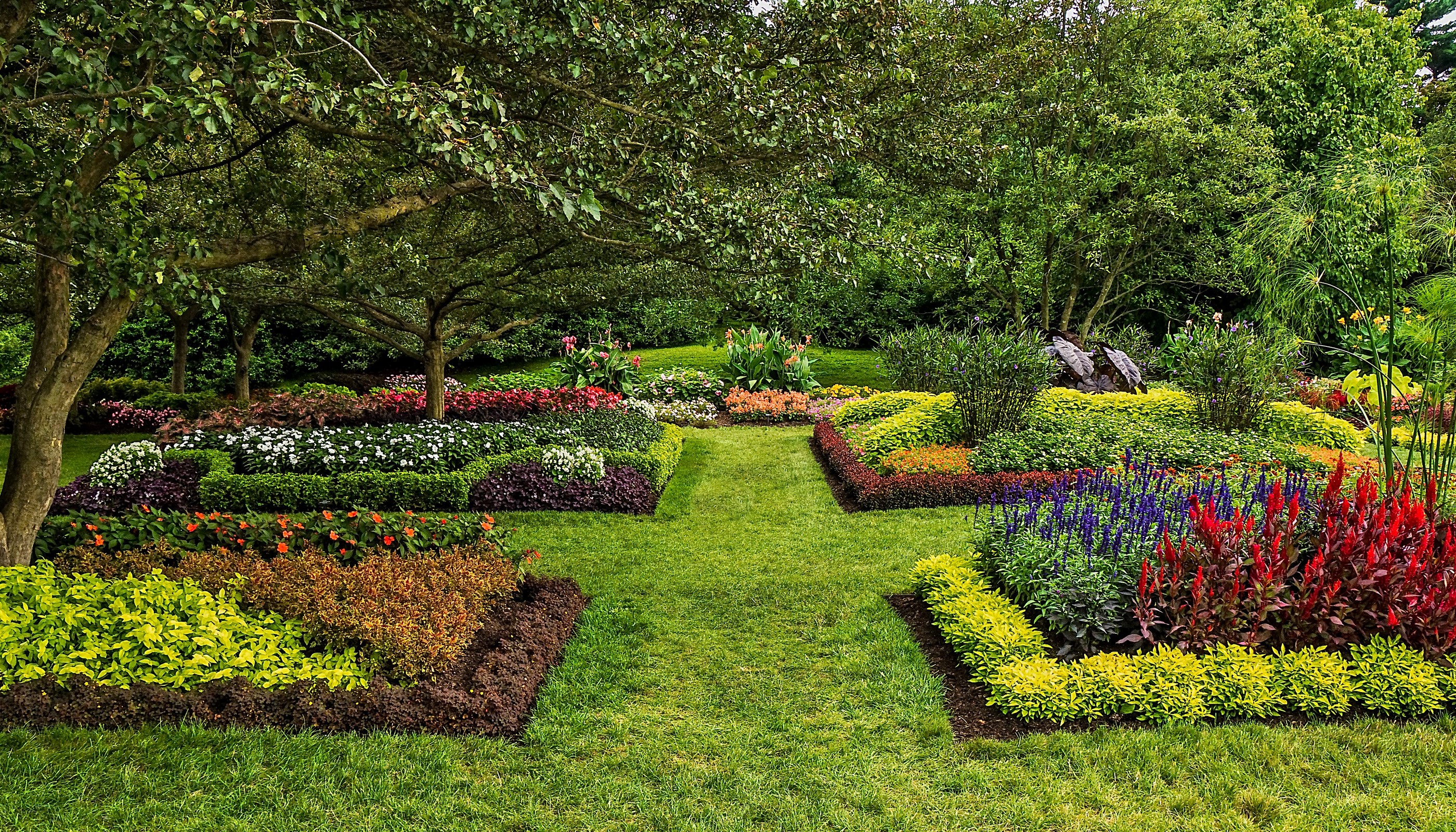 Formal garden with colorful flower beds and manicured lawns HD Wallpaper