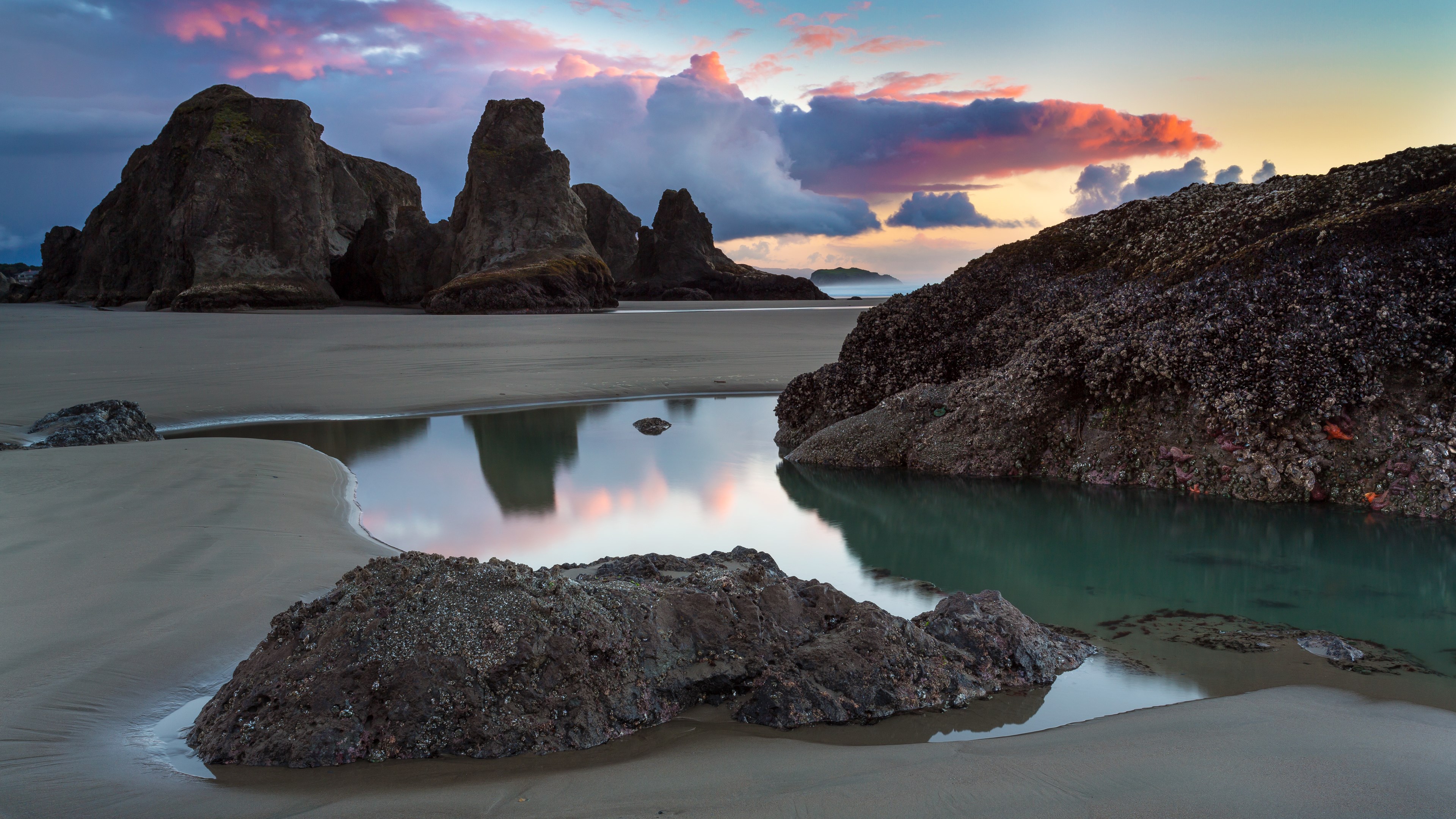 Rocky beach with tide pools and colorful sunset clouds HD Wallpaper