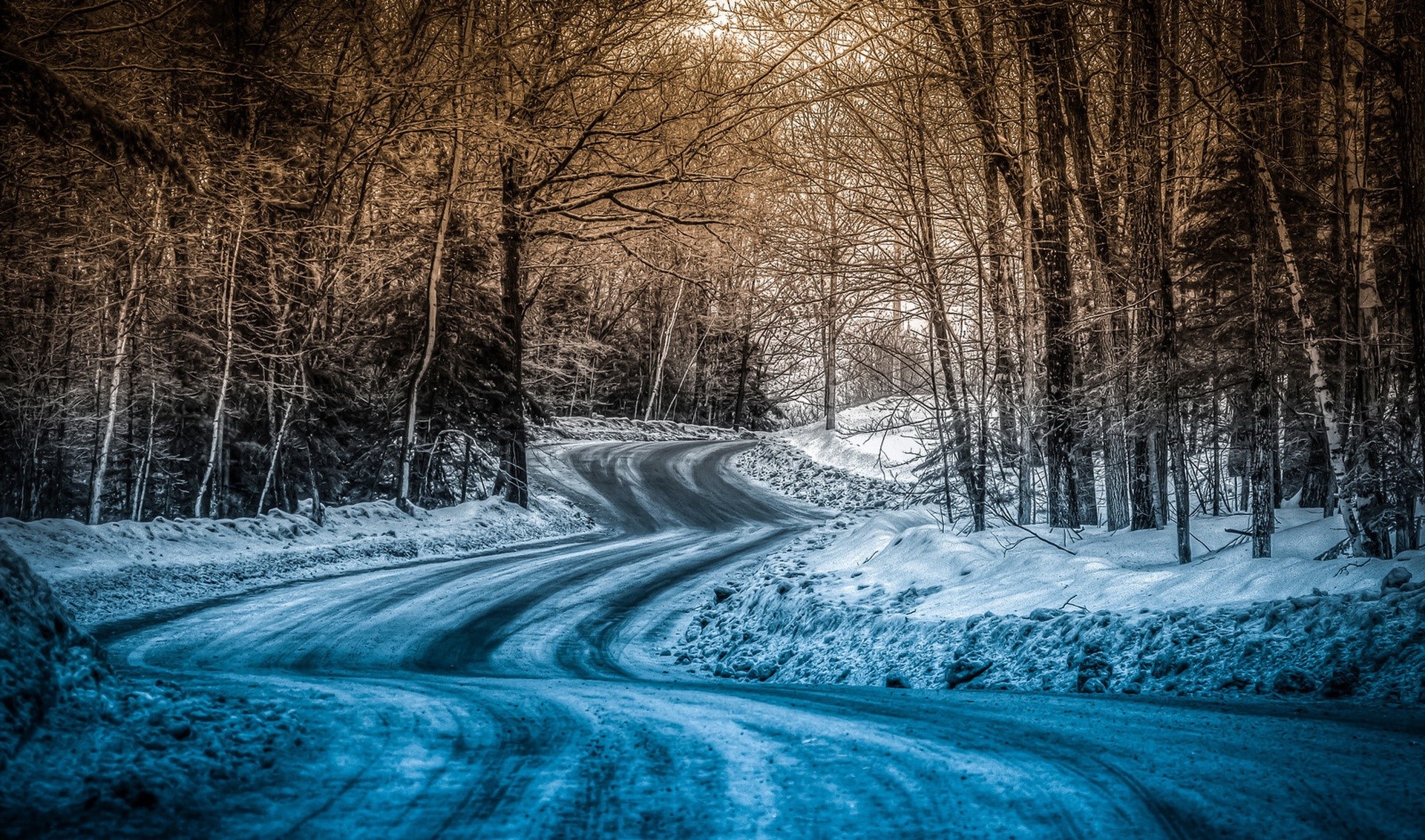 Winding snowy road through a winter forest HD Wallpaper