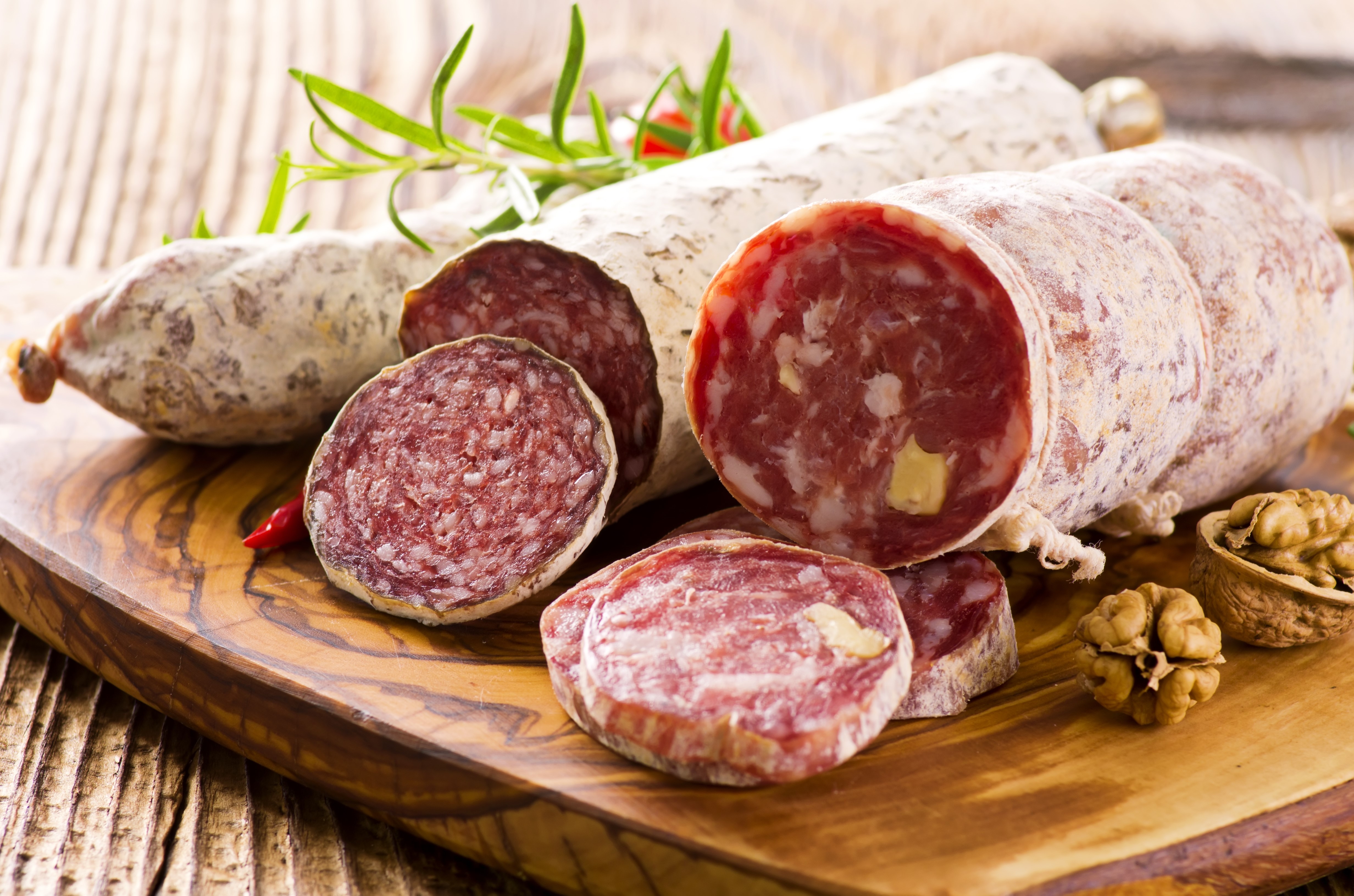 Salami with walnuts and chili peppers on a wooden board HD Wallpaper