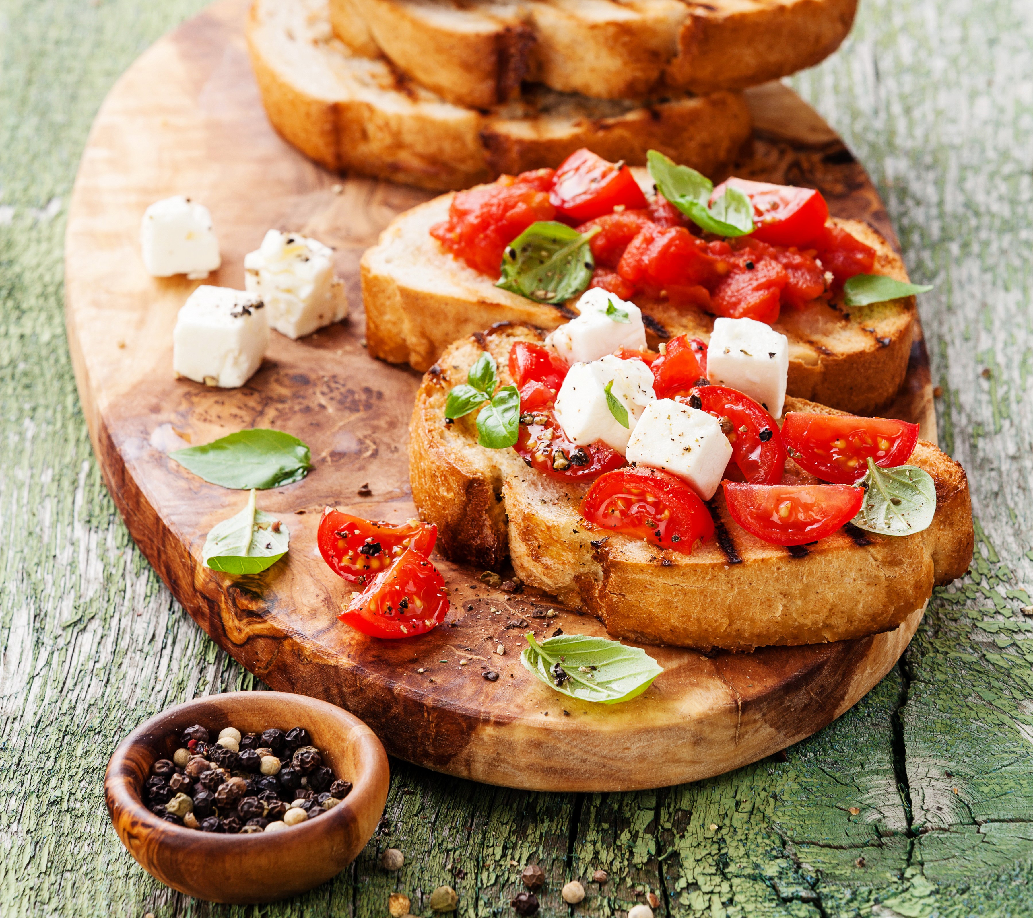 Bruschetta with tomatoes, cheese, and basil on a wooden board HD Wallpaper