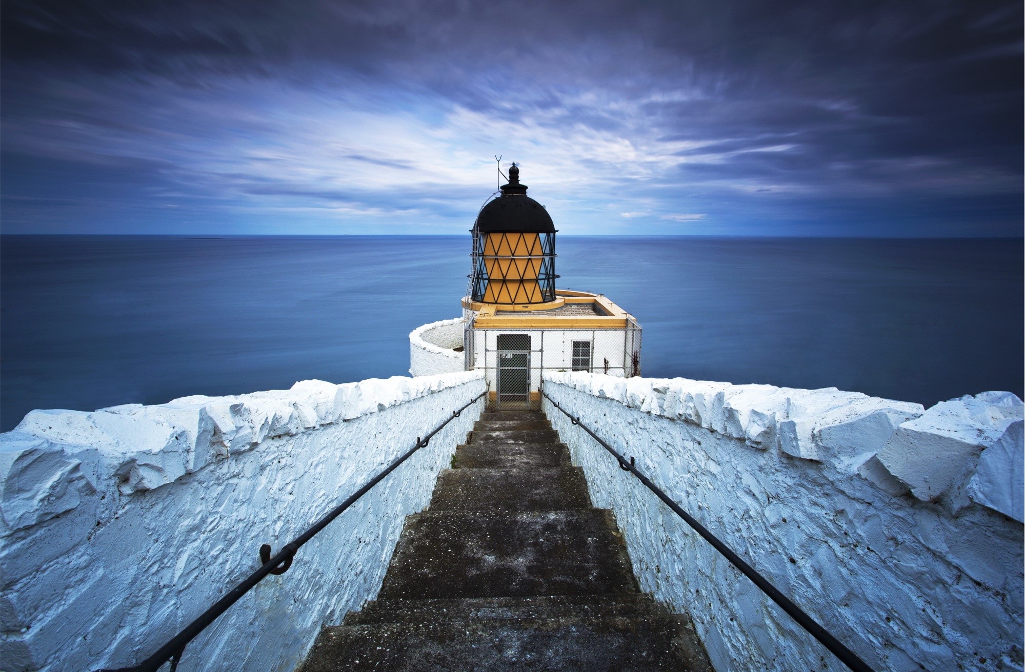 Lighthouse with stairs leading to the sea HD Wallpaper