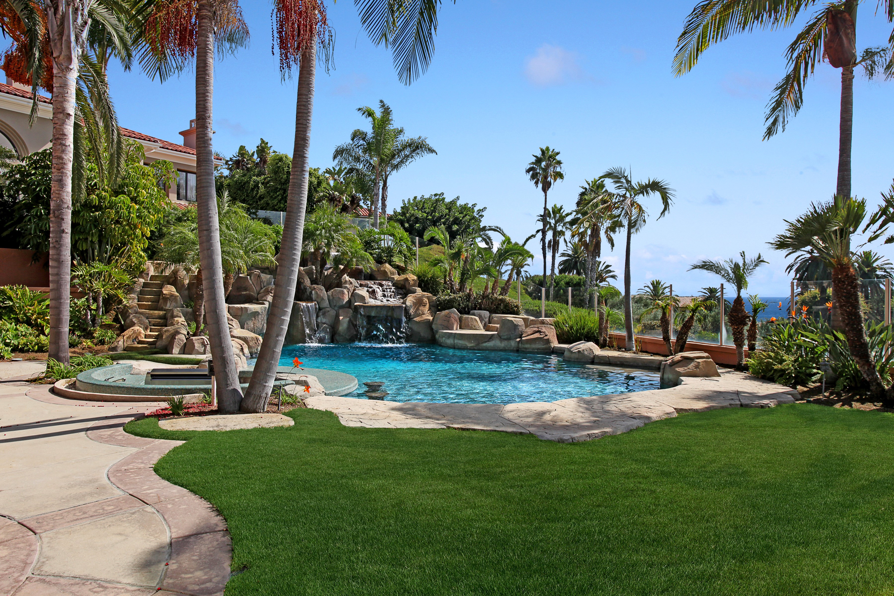 Luxury backyard with pool, waterfall, and palm trees HD Wallpaper