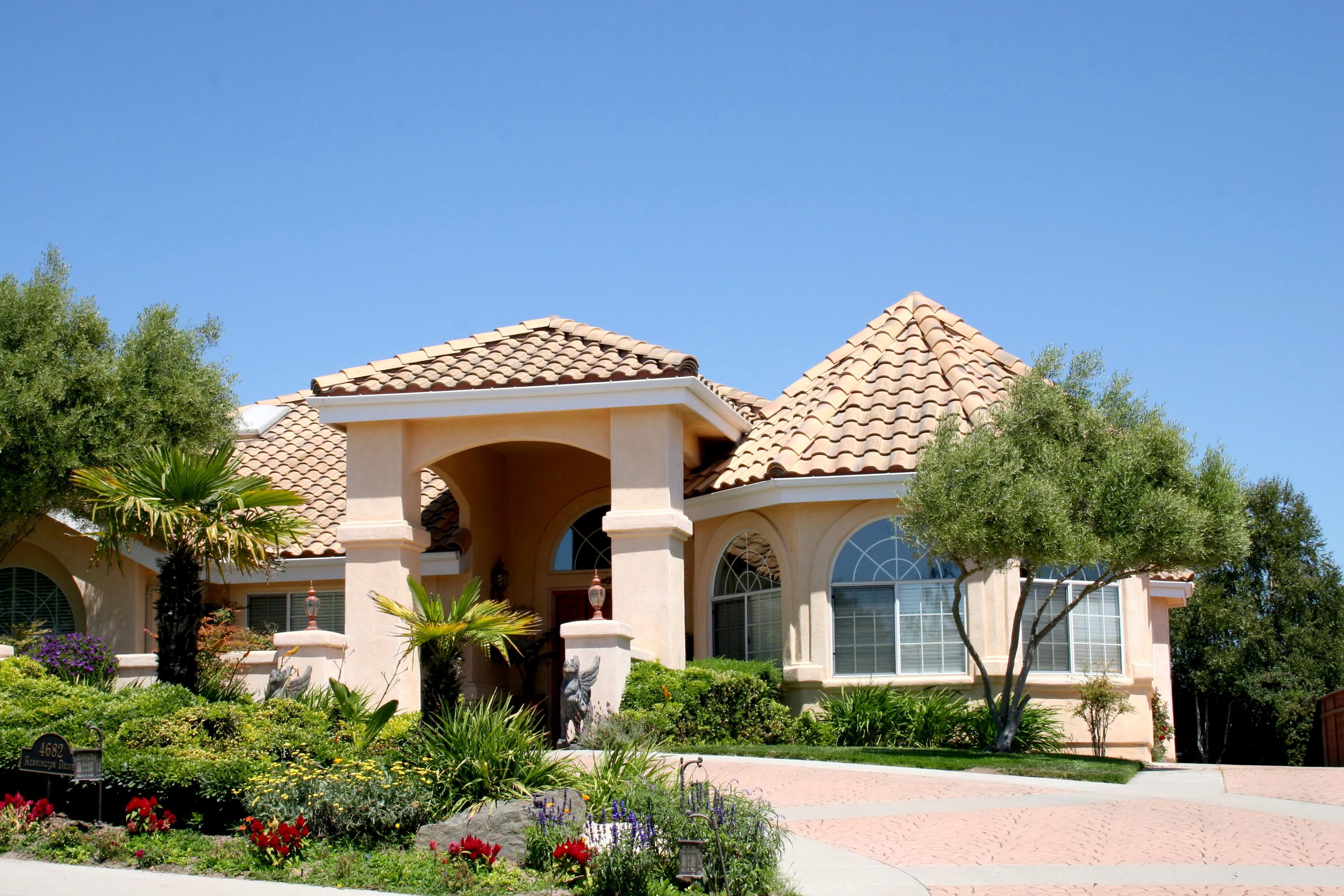 Large stucco house with tile roof and manicured landscaping HD Wallpaper