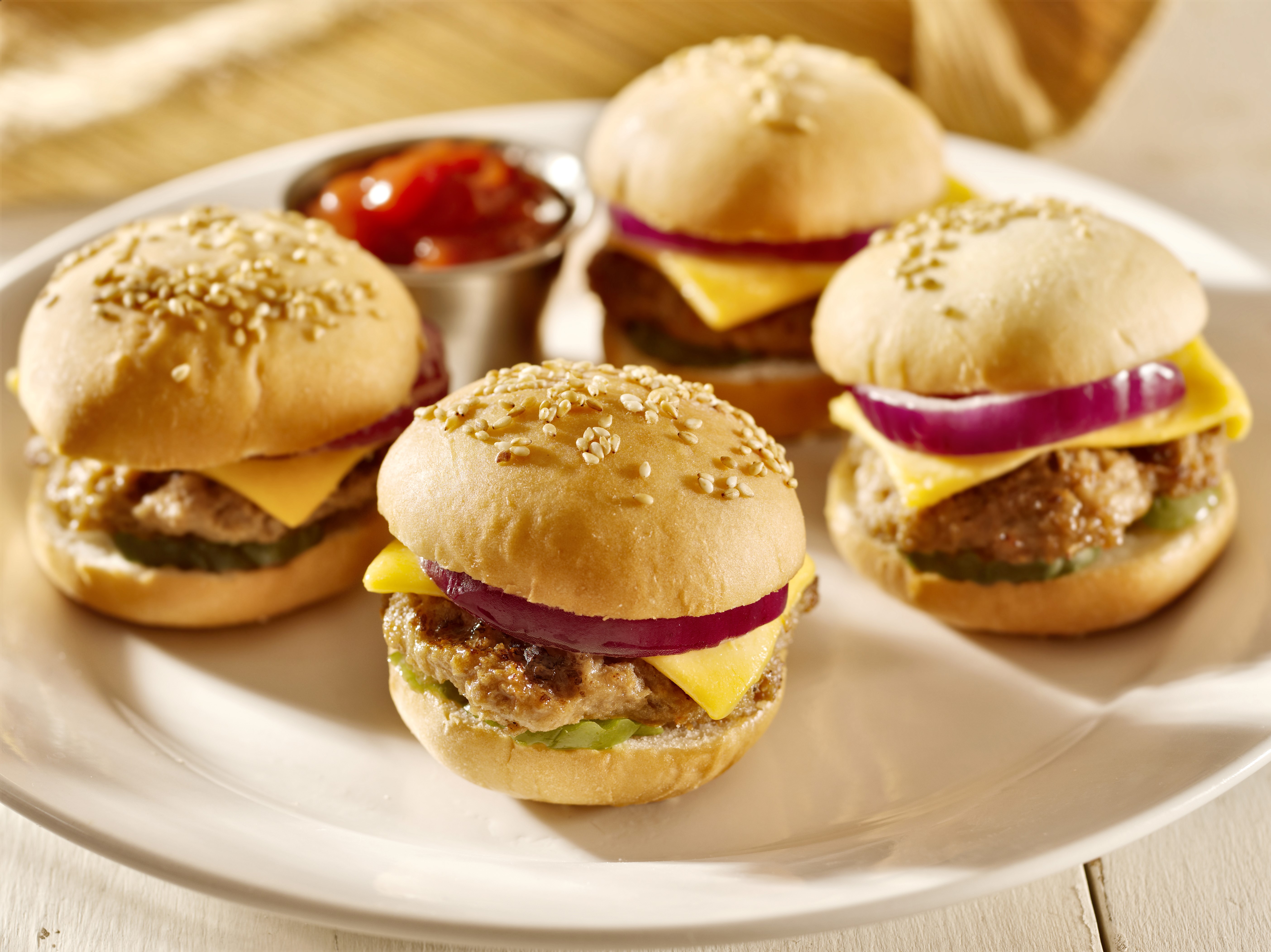 Four mini cheeseburgers with red onion and ketchup HD Wallpaper