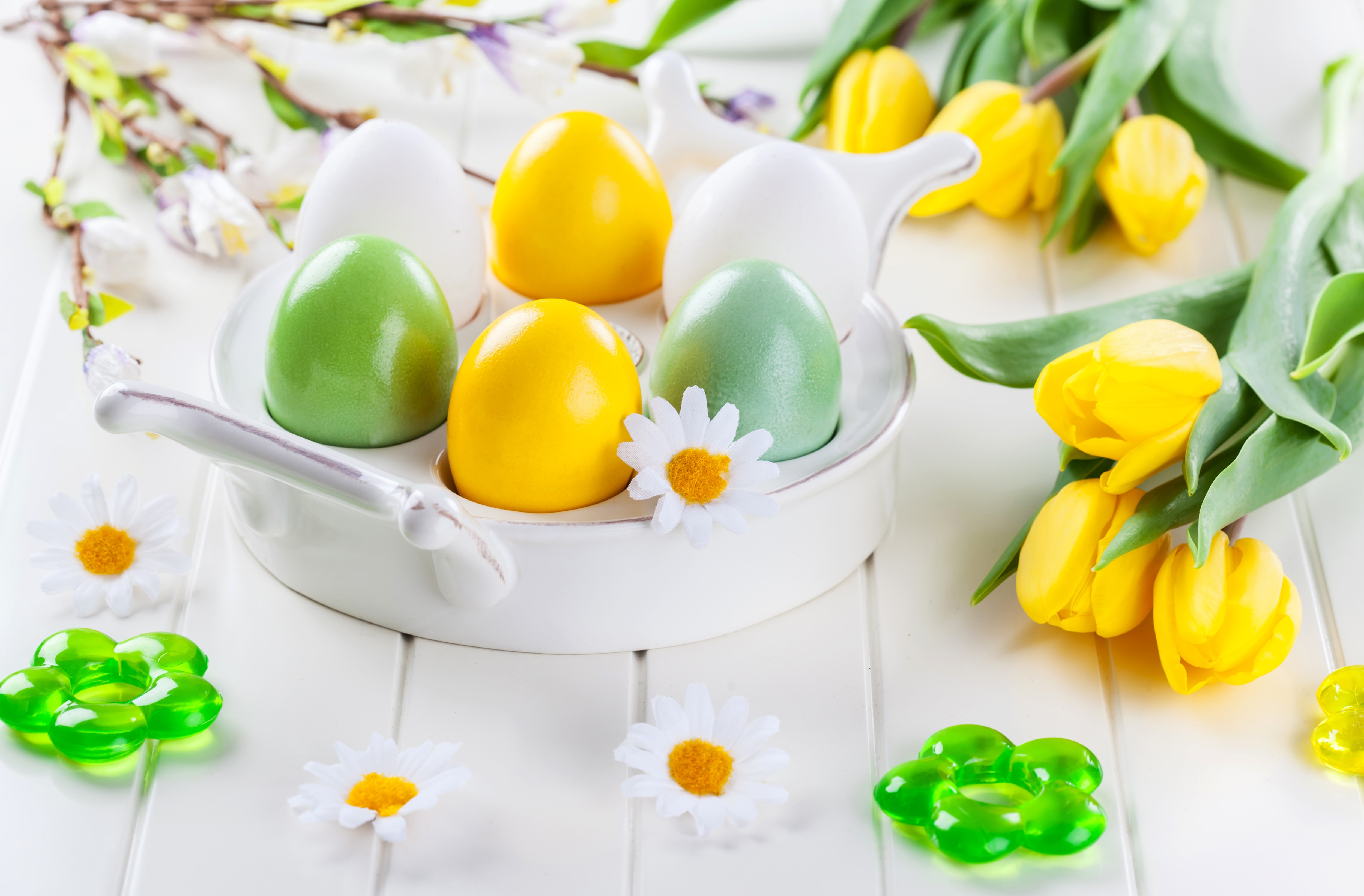 Easter eggs and yellow tulips on a white table HD Wallpaper