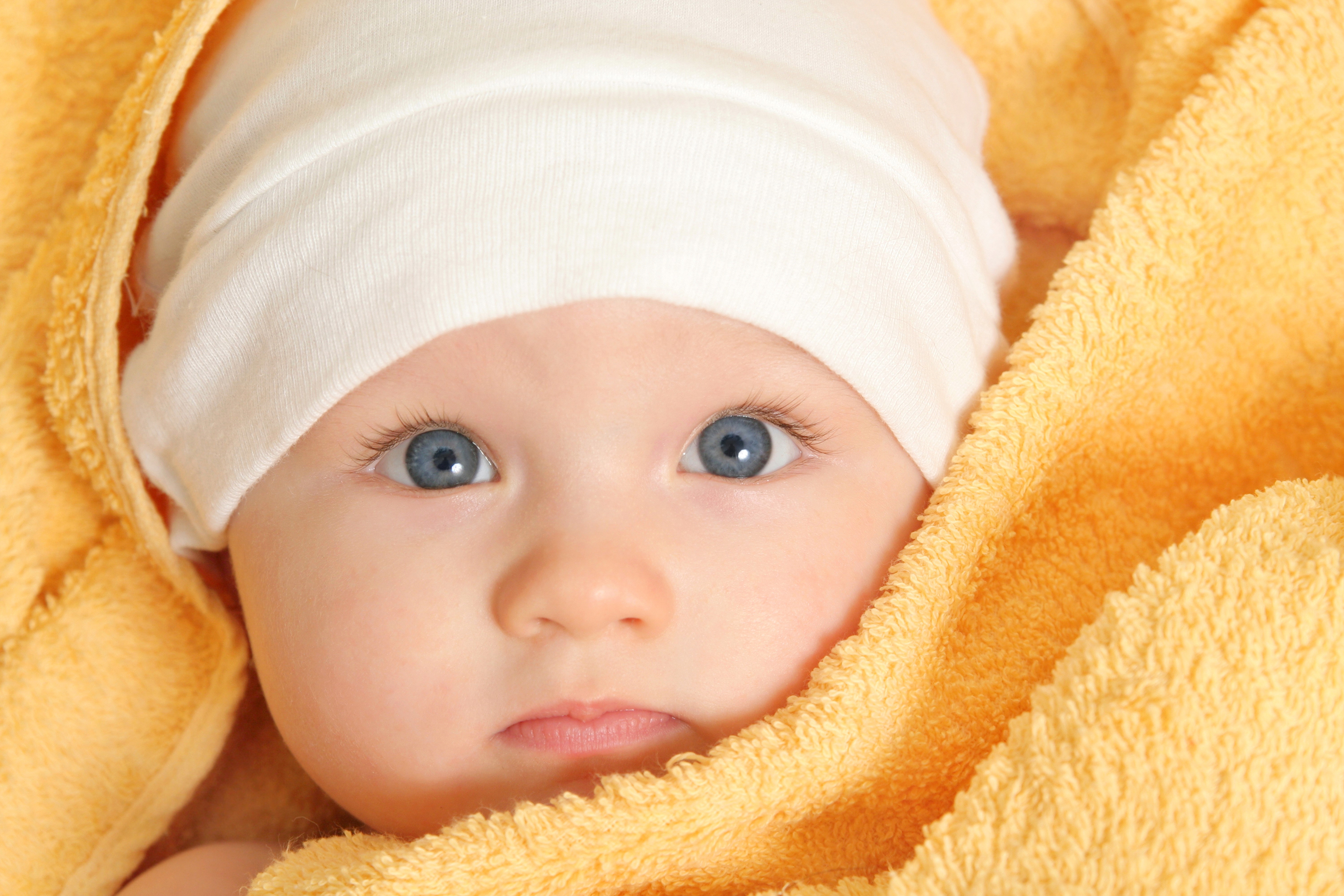 Baby wearing a winter hat wrapped in a yellow towel HD Wallpaper