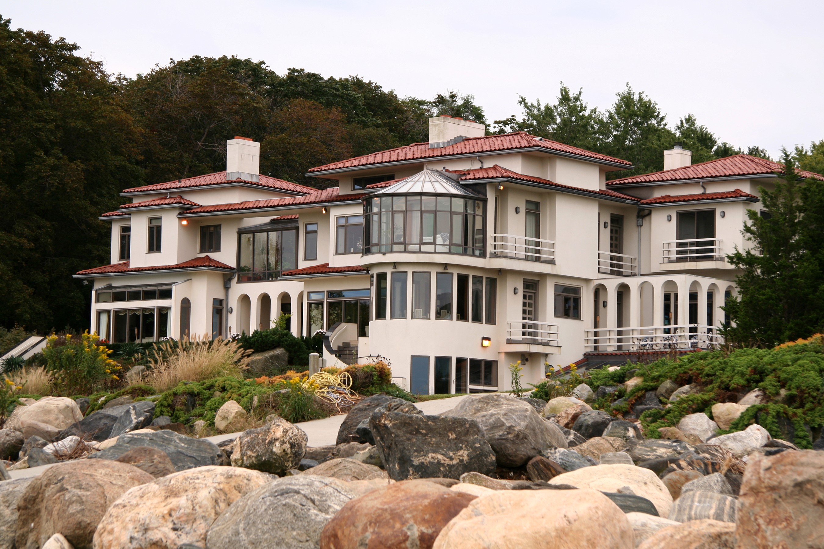 Large white mansion with red tile roof on rocky shore HD Wallpaper