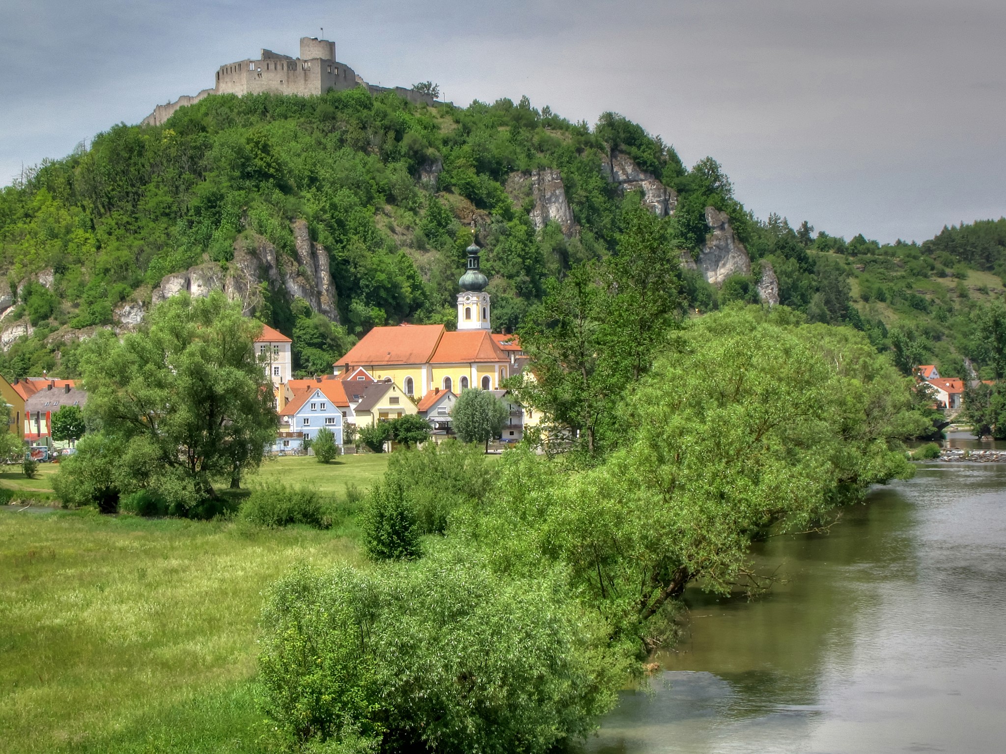 Castle and village on a hill overlooking a river HD Wallpaper