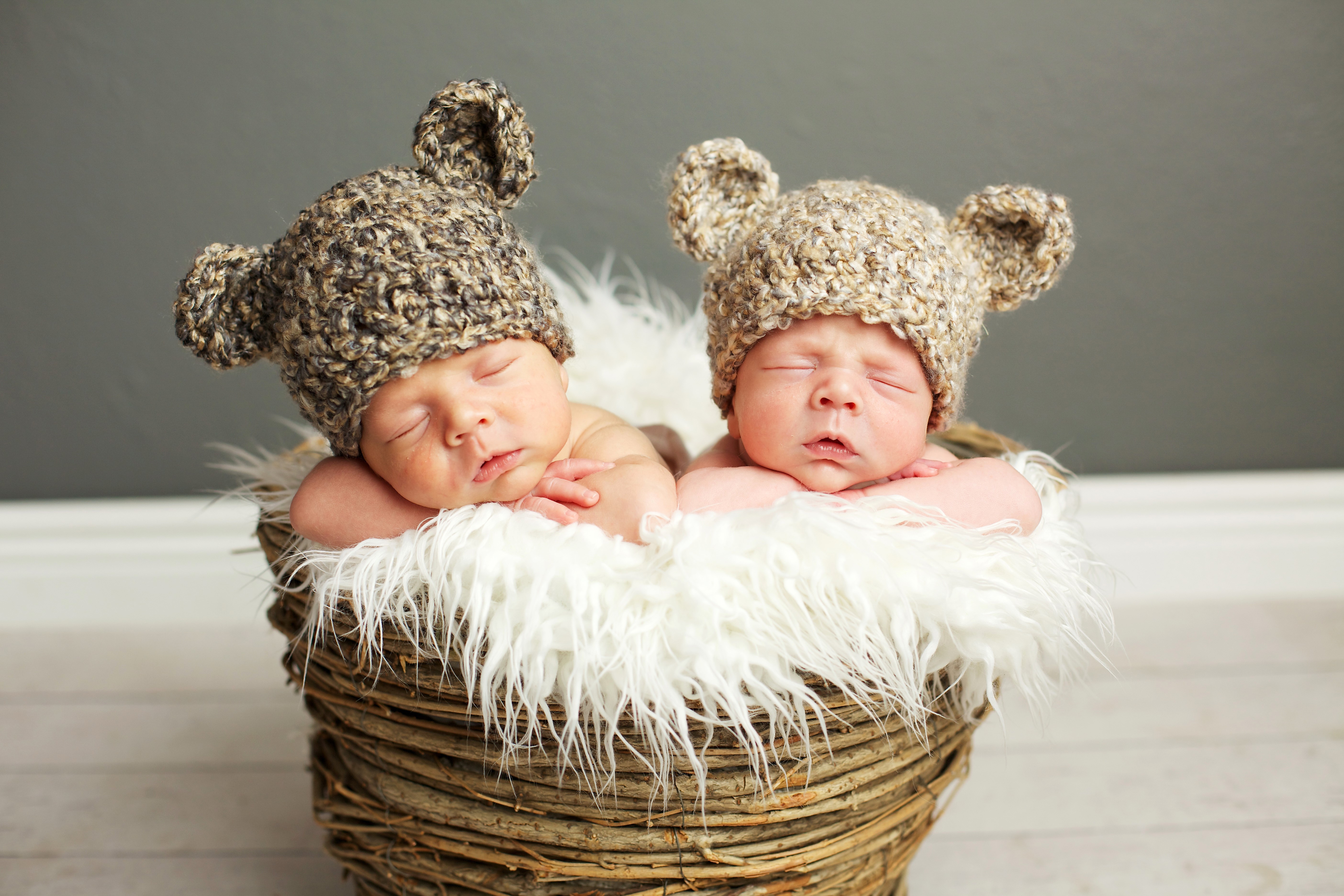 Two sleeping infants in bear hats in a basket HD Wallpaper