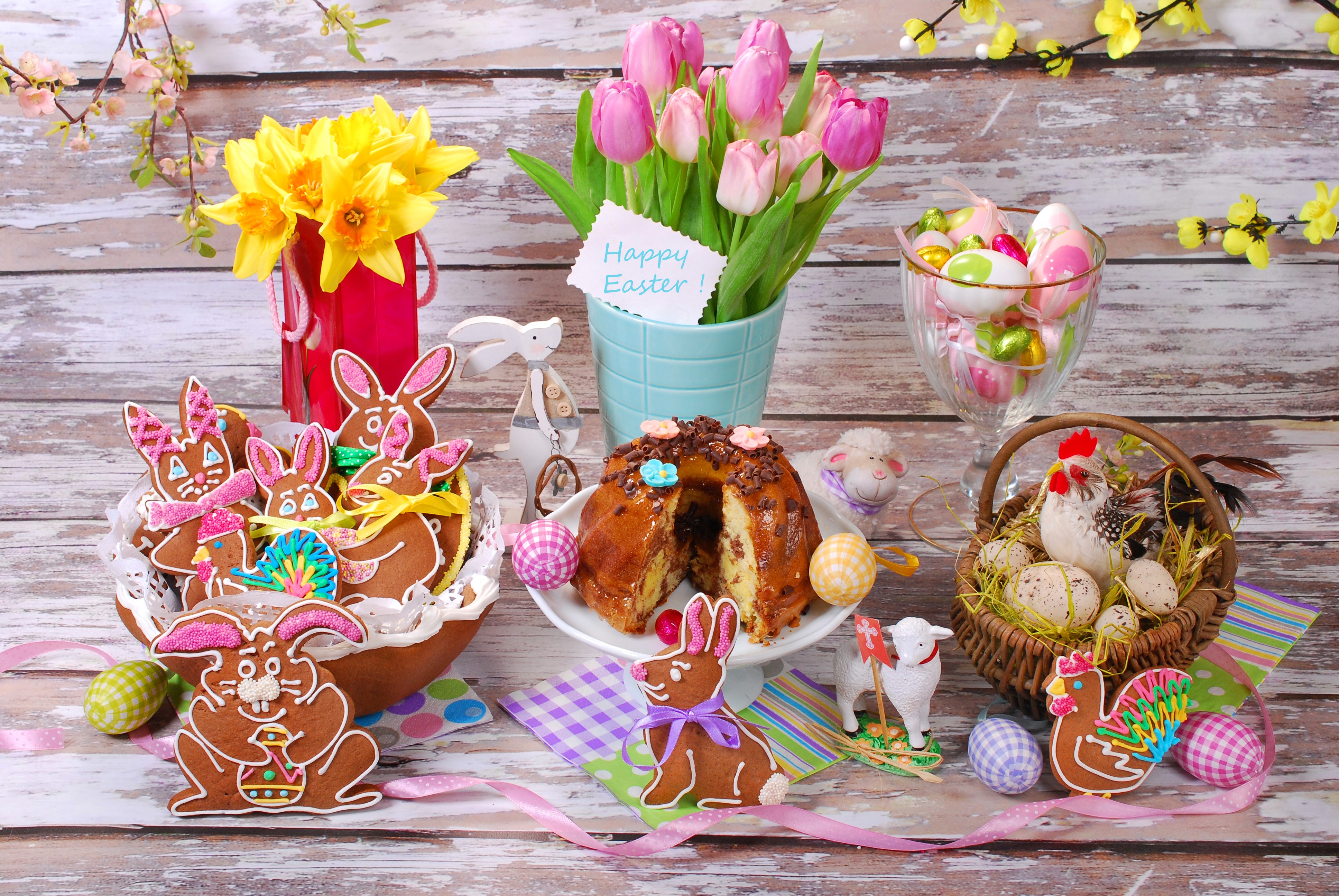 Easter table with tulips, daffodils, cookies, cake, and eggs HD Wallpaper