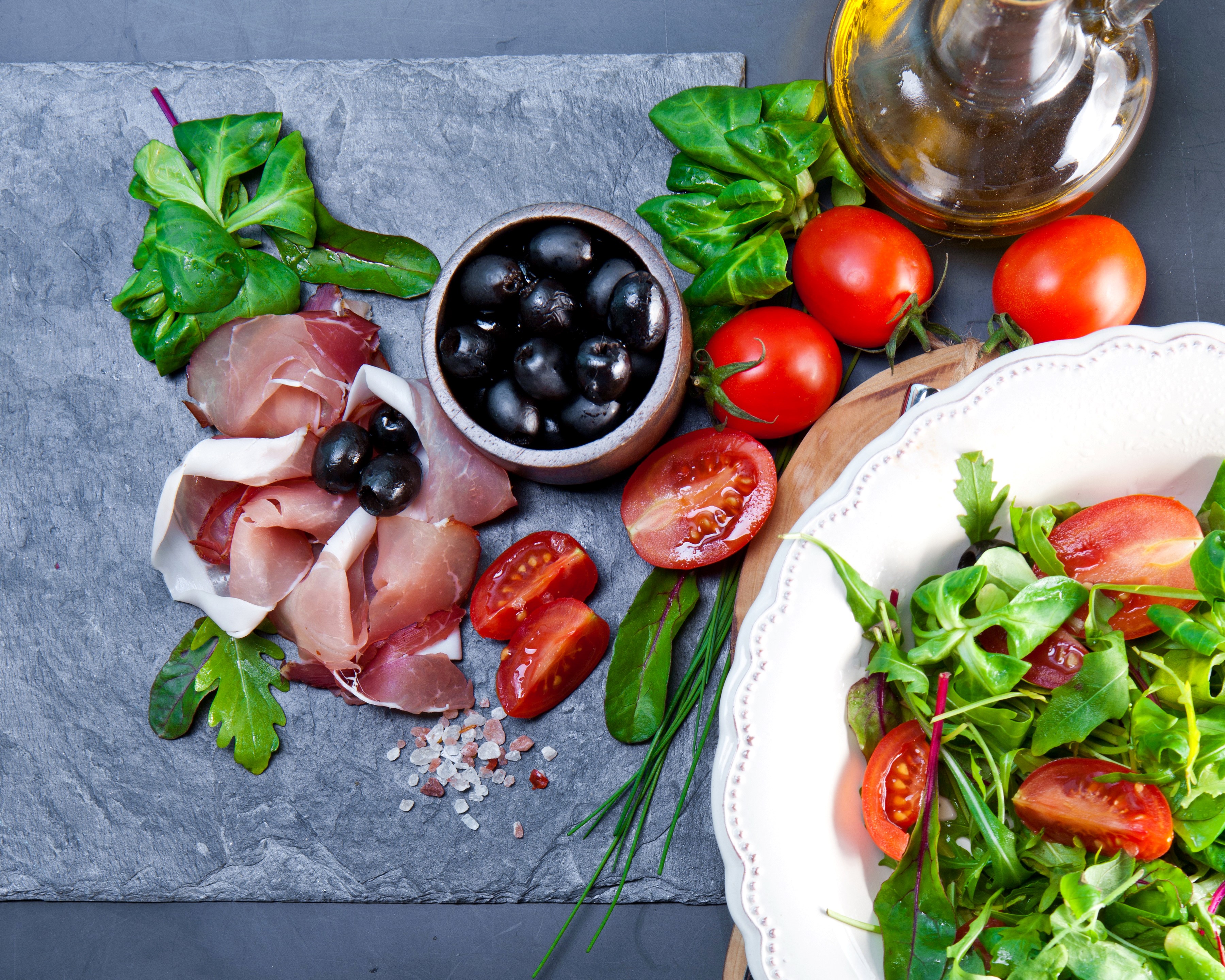 Prosciutto, olives, tomatoes, and salad on a slate board HD Wallpaper