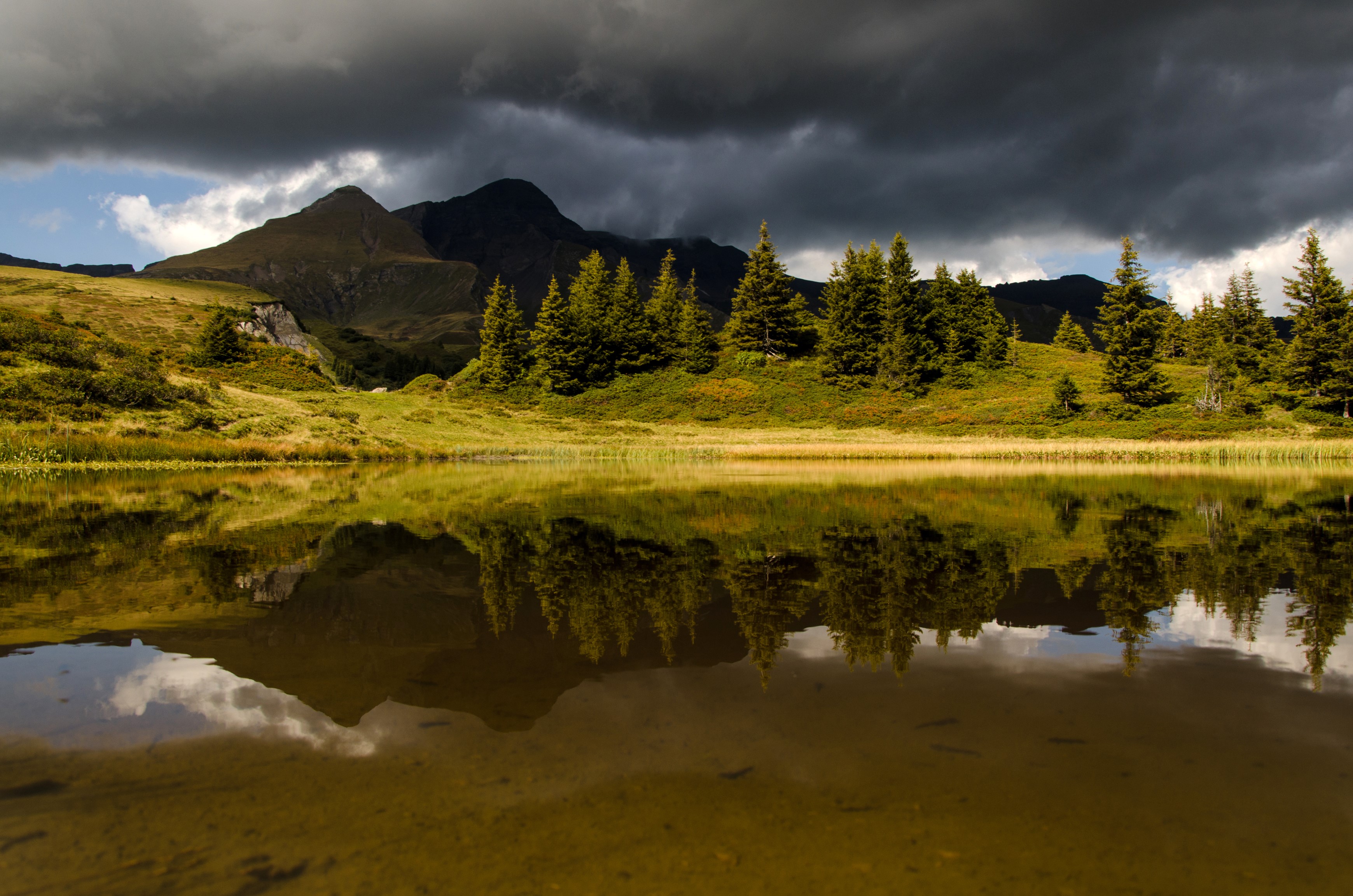 Mountain lake reflection with dark clouds in Switzerland HD Wallpaper