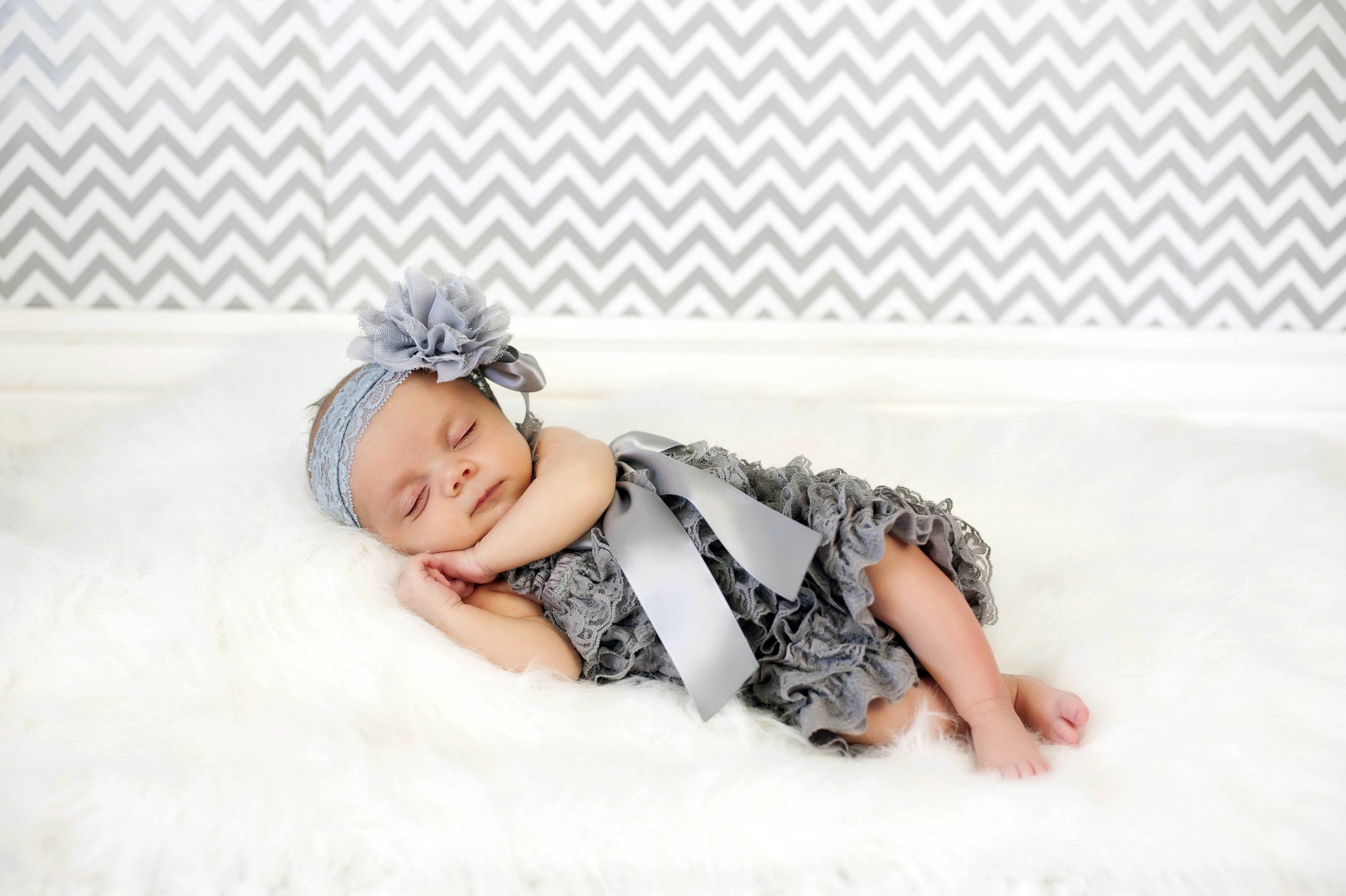 Baby girl sleeping on white fur with grey headband HD Wallpaper