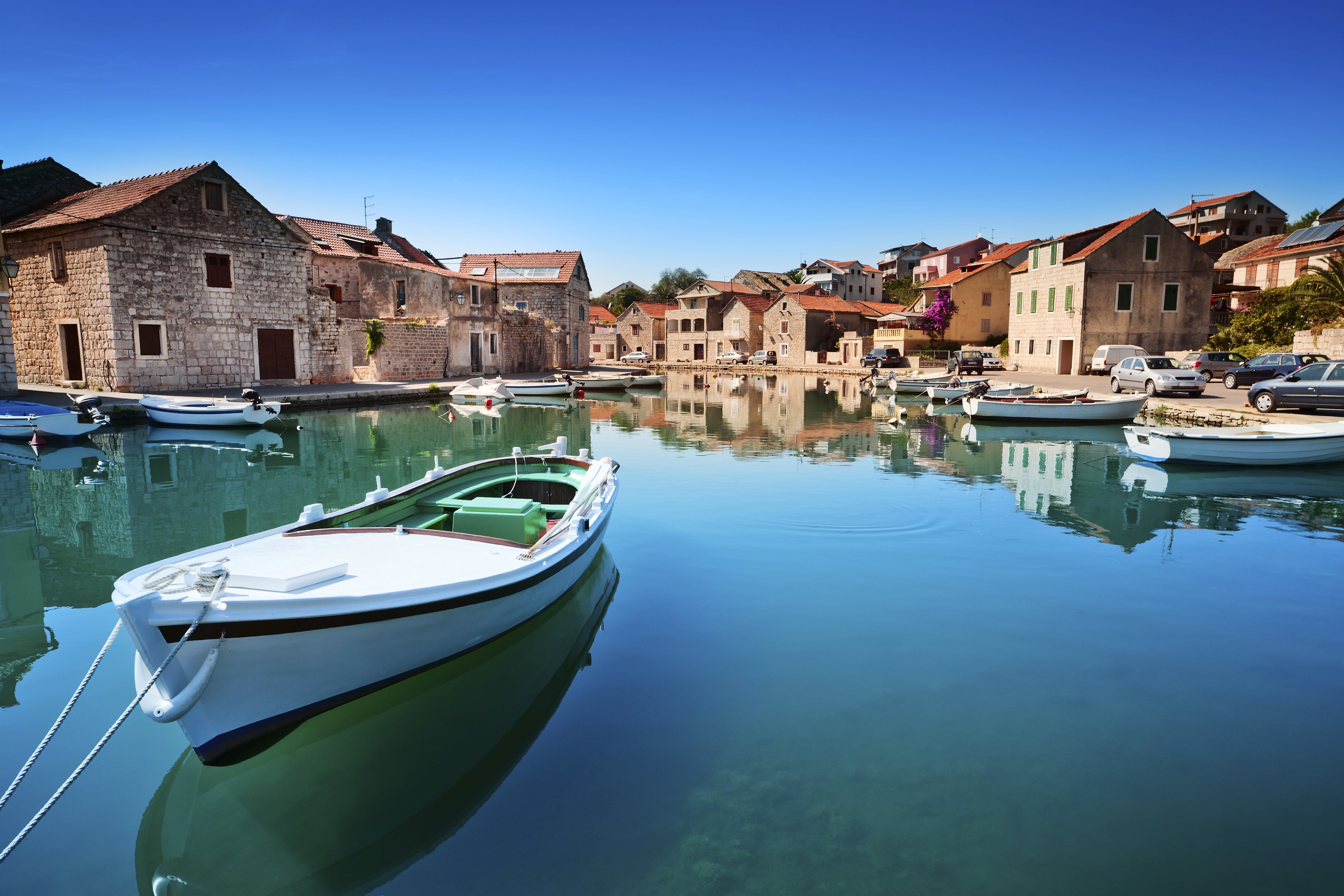 Boats docked in a Croatian harbor with stone houses HD Wallpaper