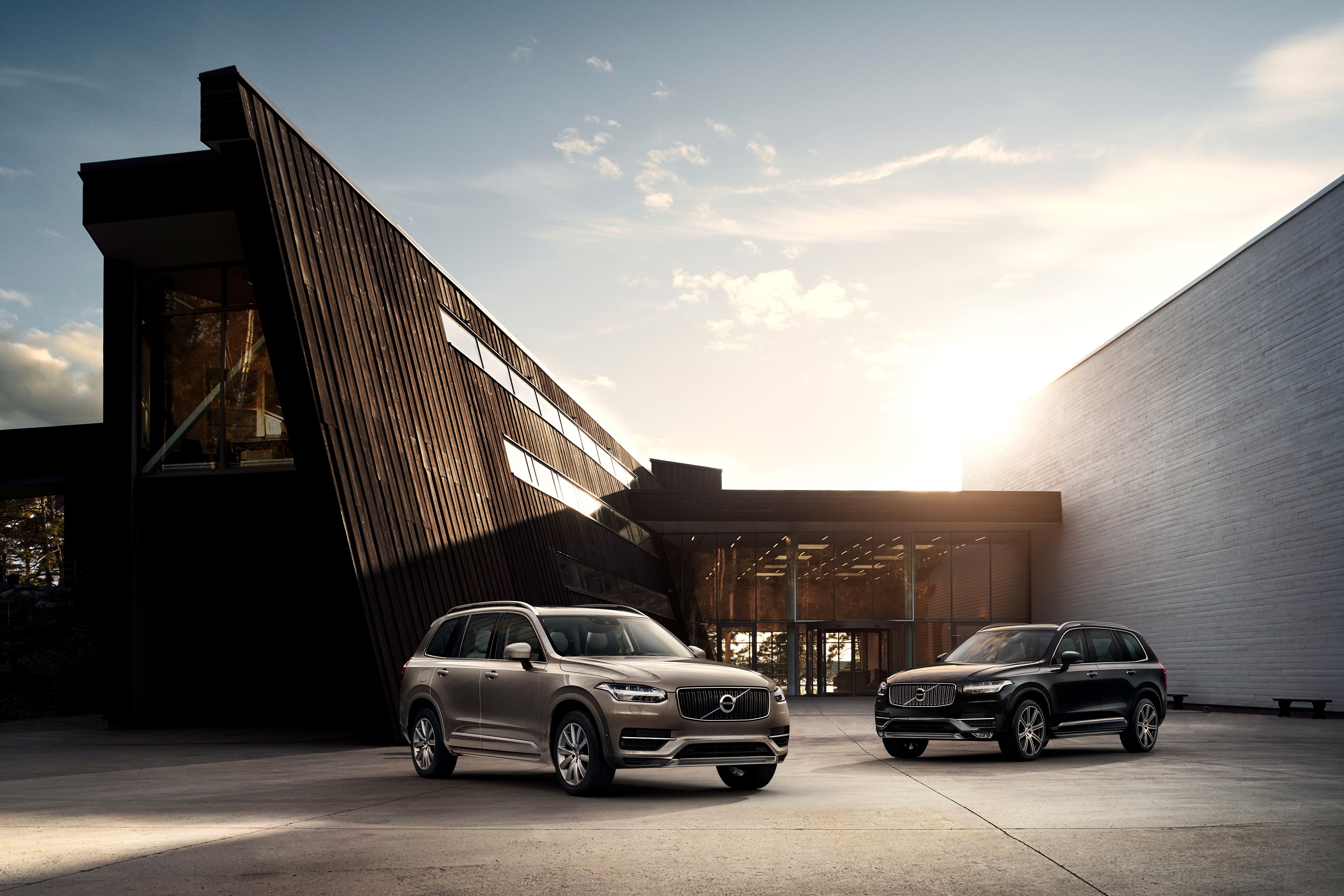 Two Volvo XC90 SUVs outside modern building HD Wallpaper
