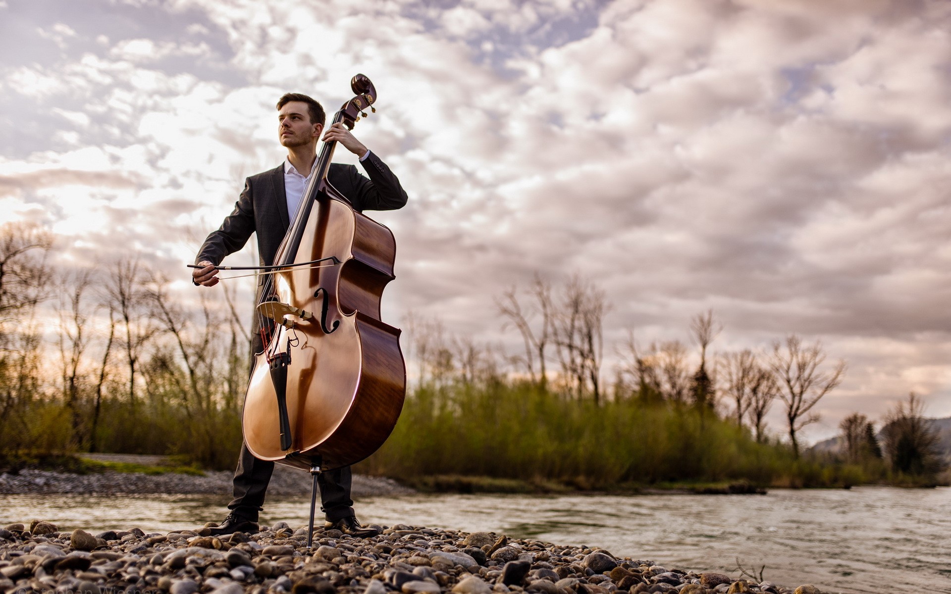 Man playing double bass by a river HD Wallpaper