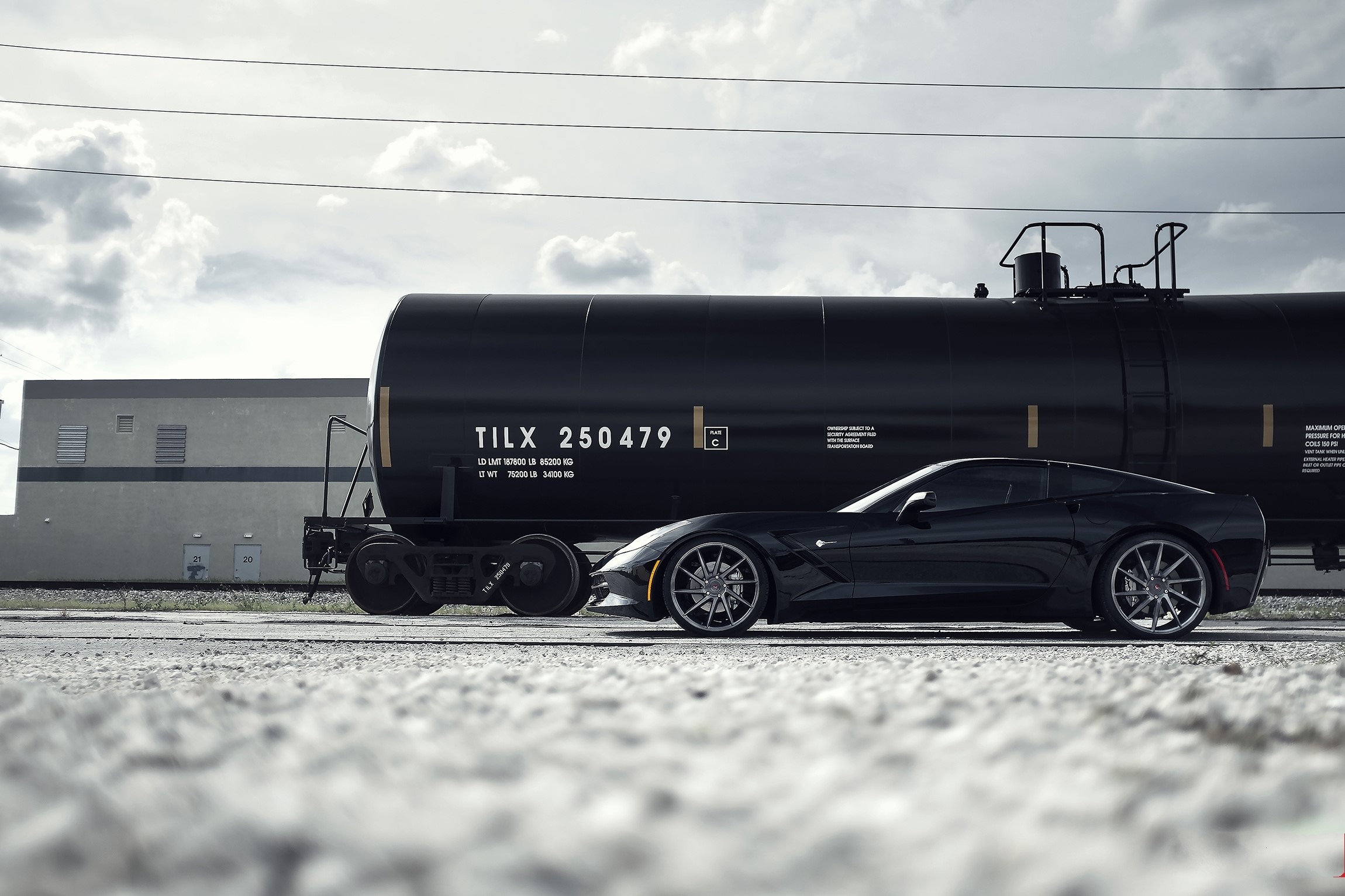 Black Chevrolet Corvette C7 next to train cistern HD Wallpaper