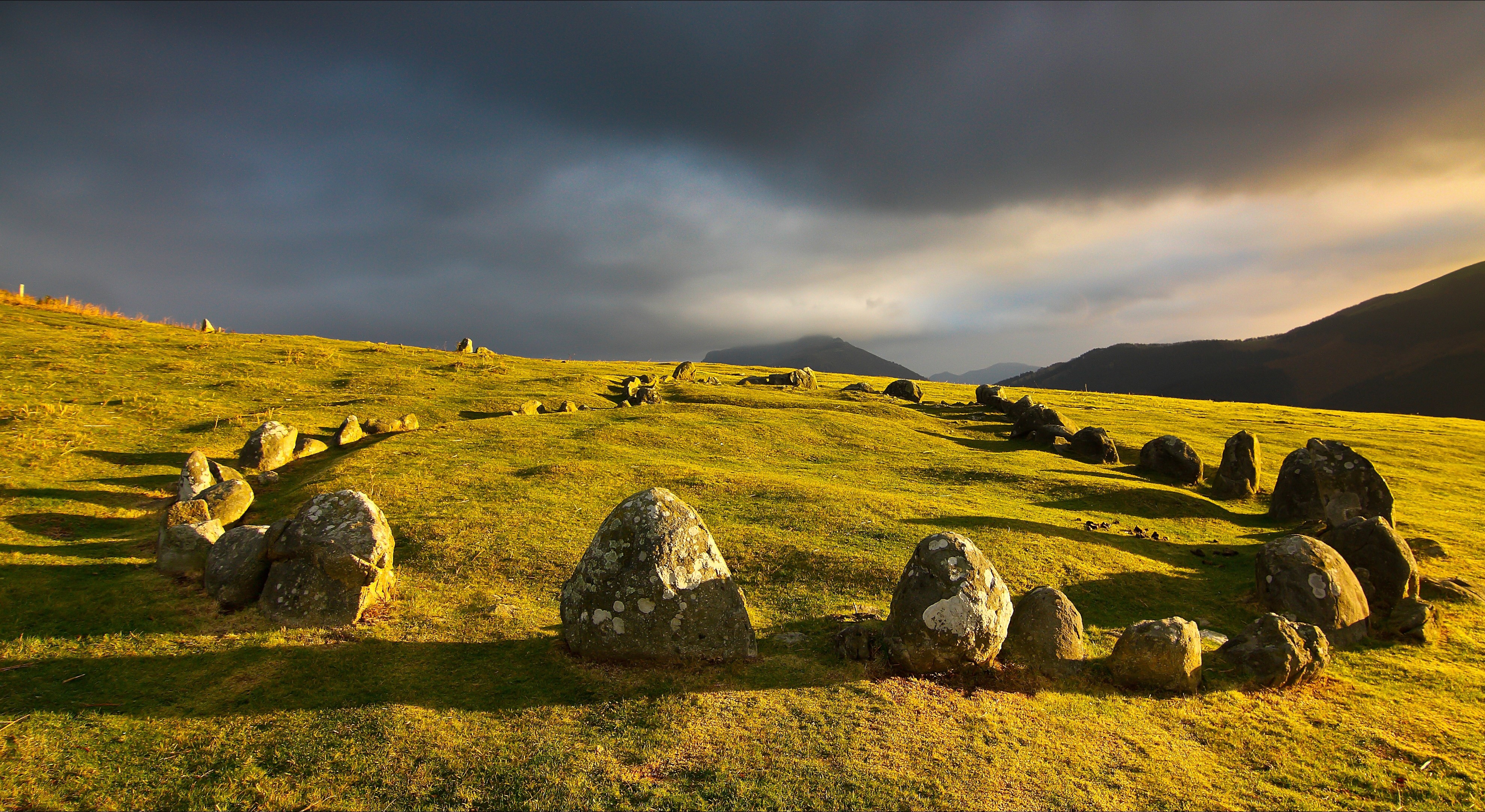 Standing Stones on a Grassy Hill Under a Thunderous Sky HD Wallpaper