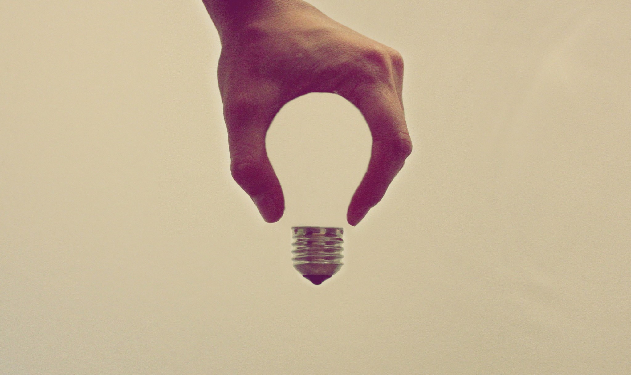 Hand holding a light bulb base HD Wallpaper