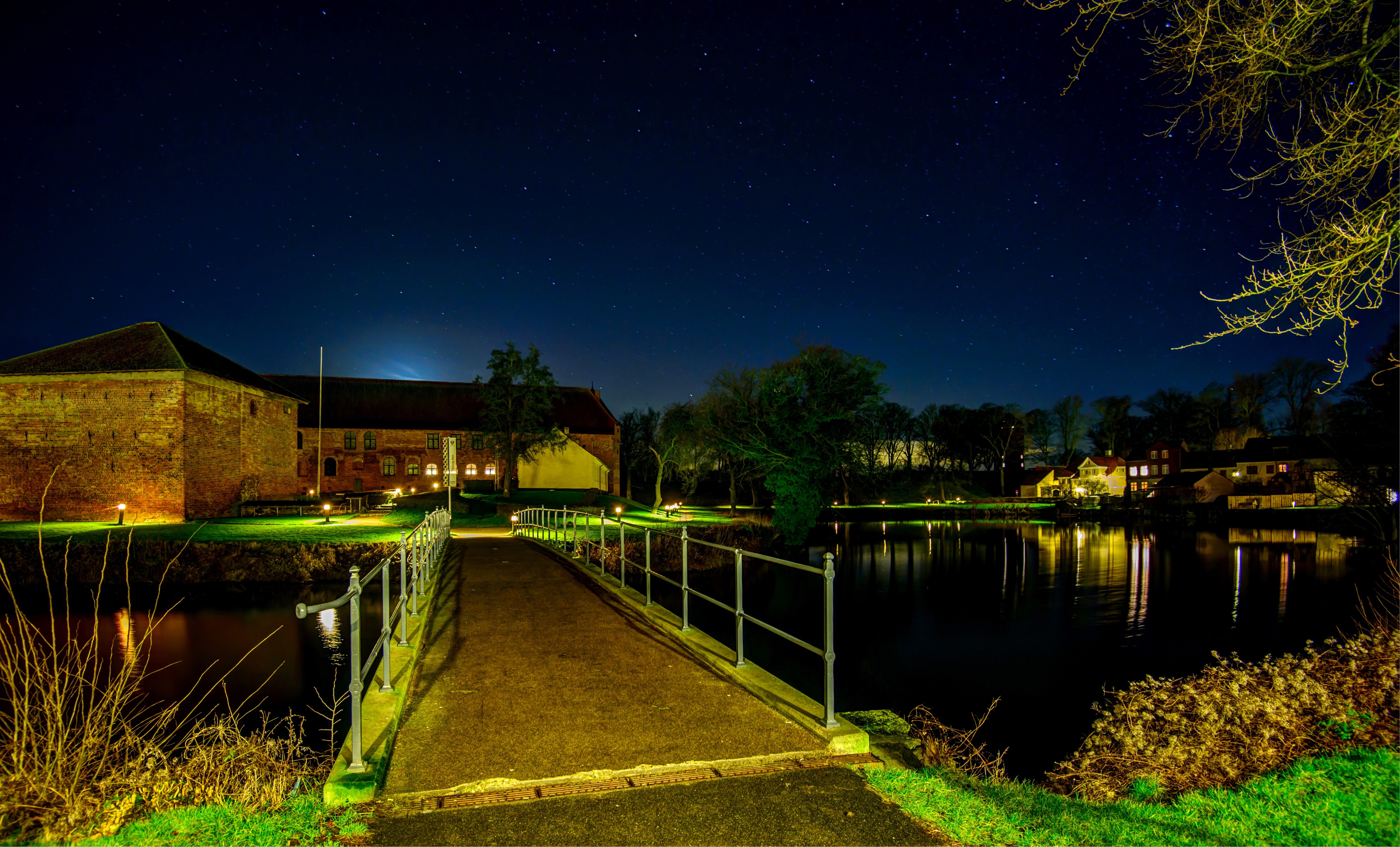 Brick building and bridge over water at night HD Wallpaper