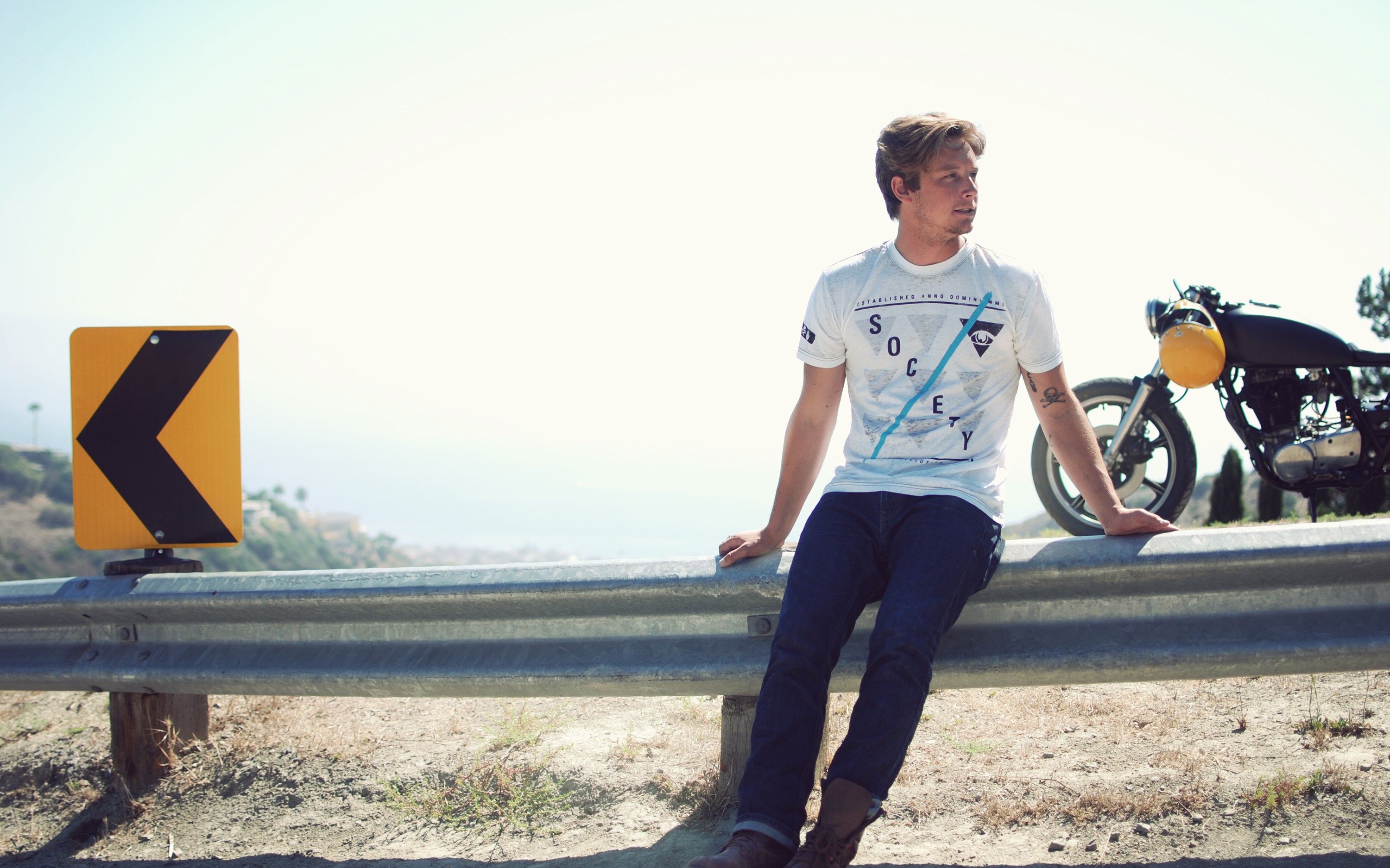 Man sitting on guardrail with motorcycle HD Wallpaper