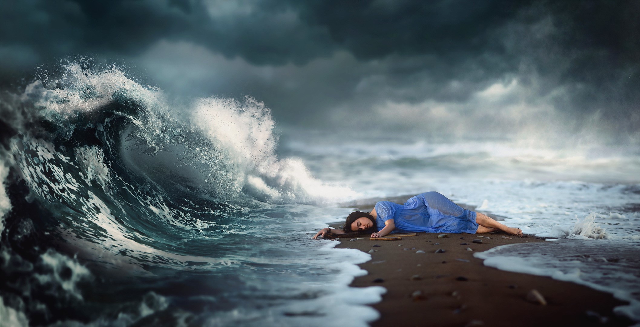 Woman in blue dress lying on beach with large wave HD Wallpaper