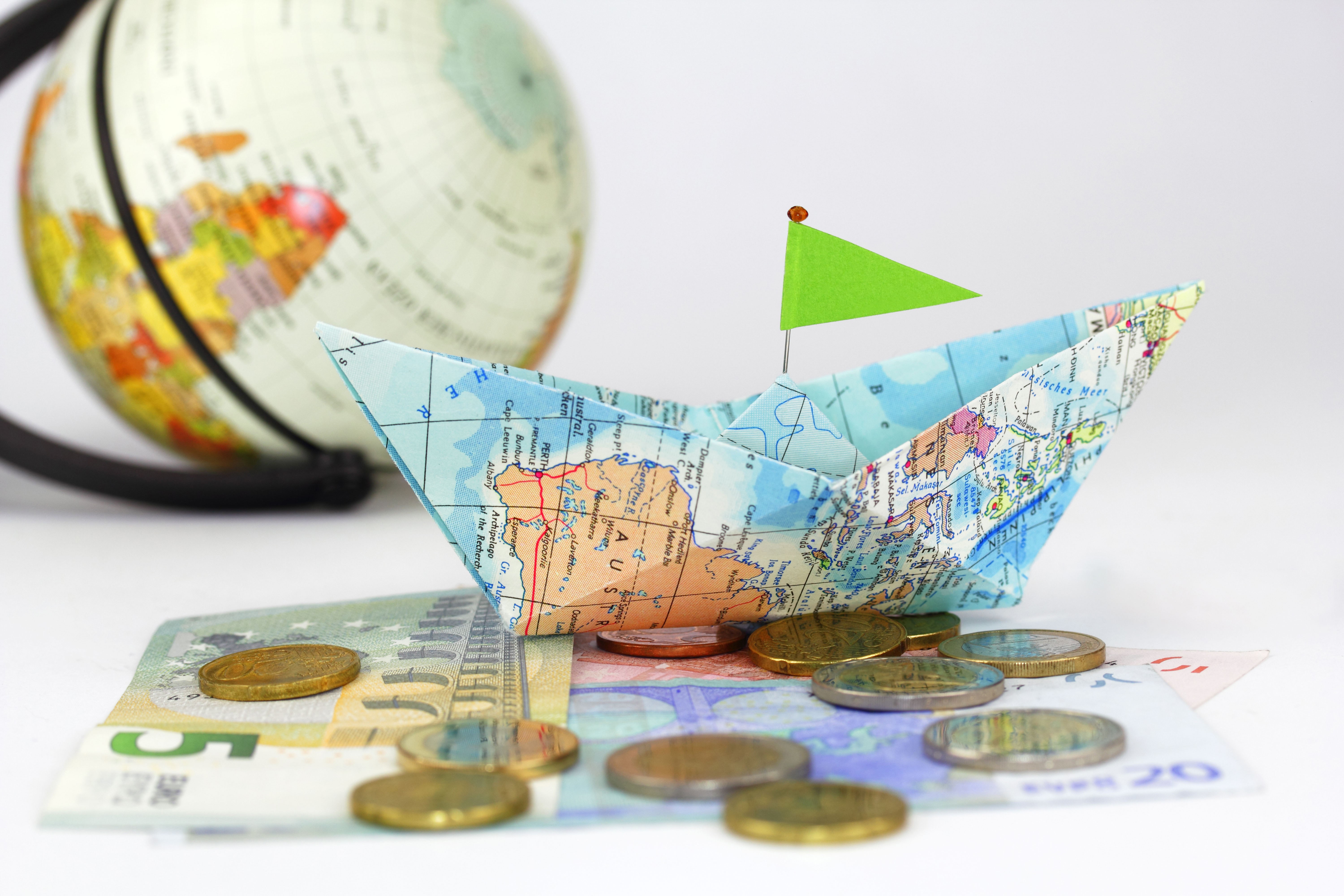 Paper boat with map on money and globe HD Wallpaper