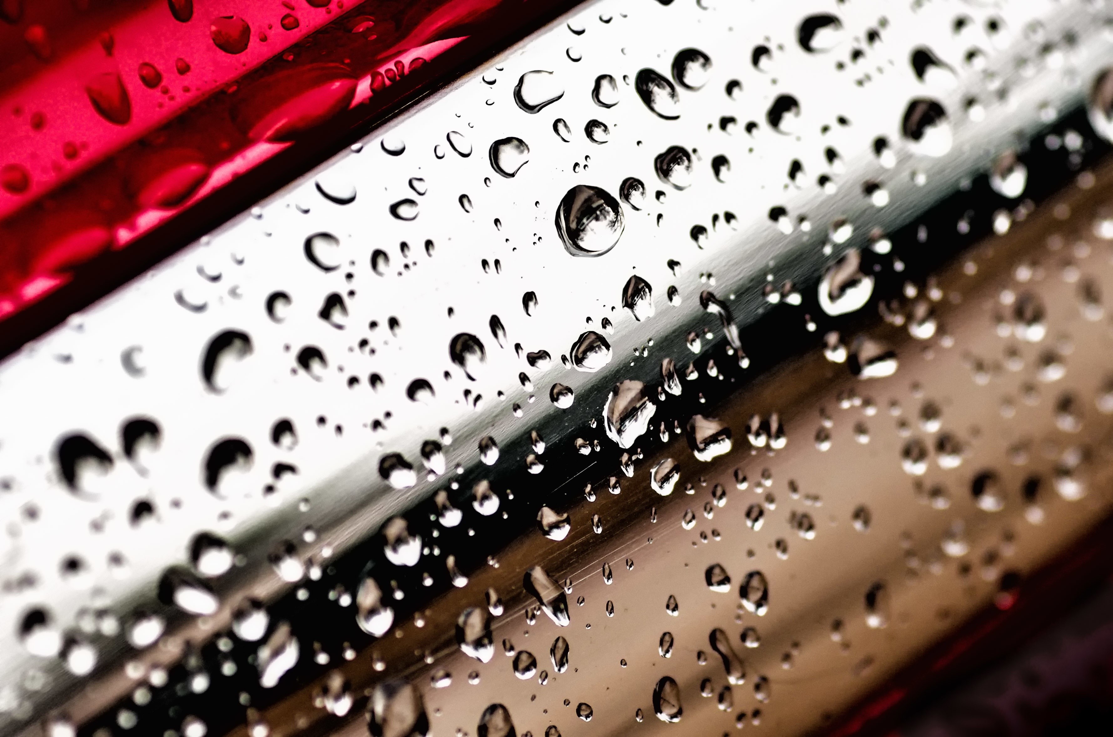 Water drops on a metallic surface with red accents HD Wallpaper
