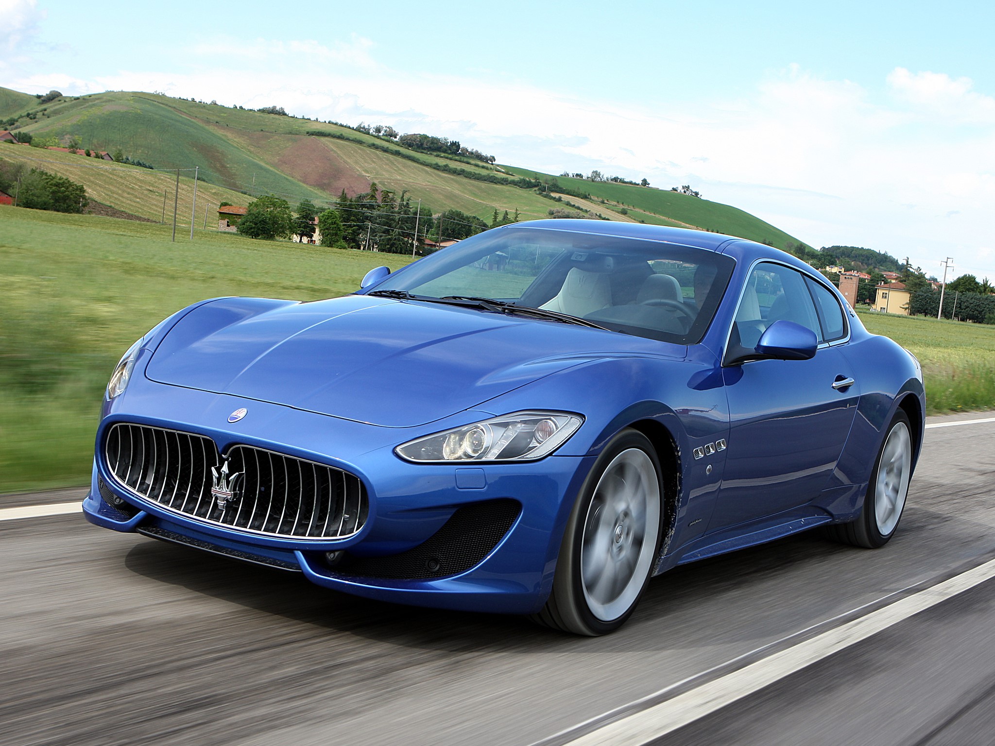 Blue Maserati GranTurismo driving on a road HD Wallpaper