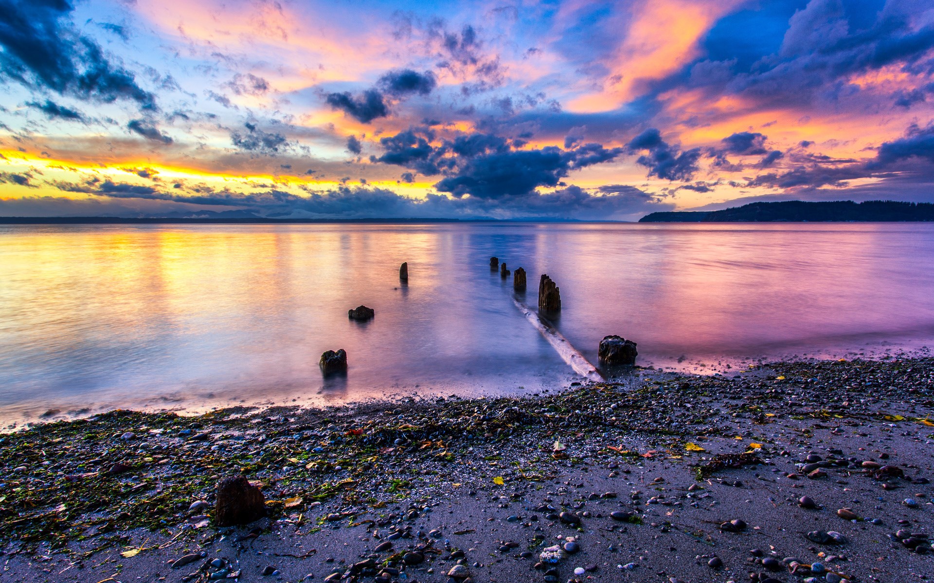 Sunset over a calm body of water with wooden posts HD Wallpaper