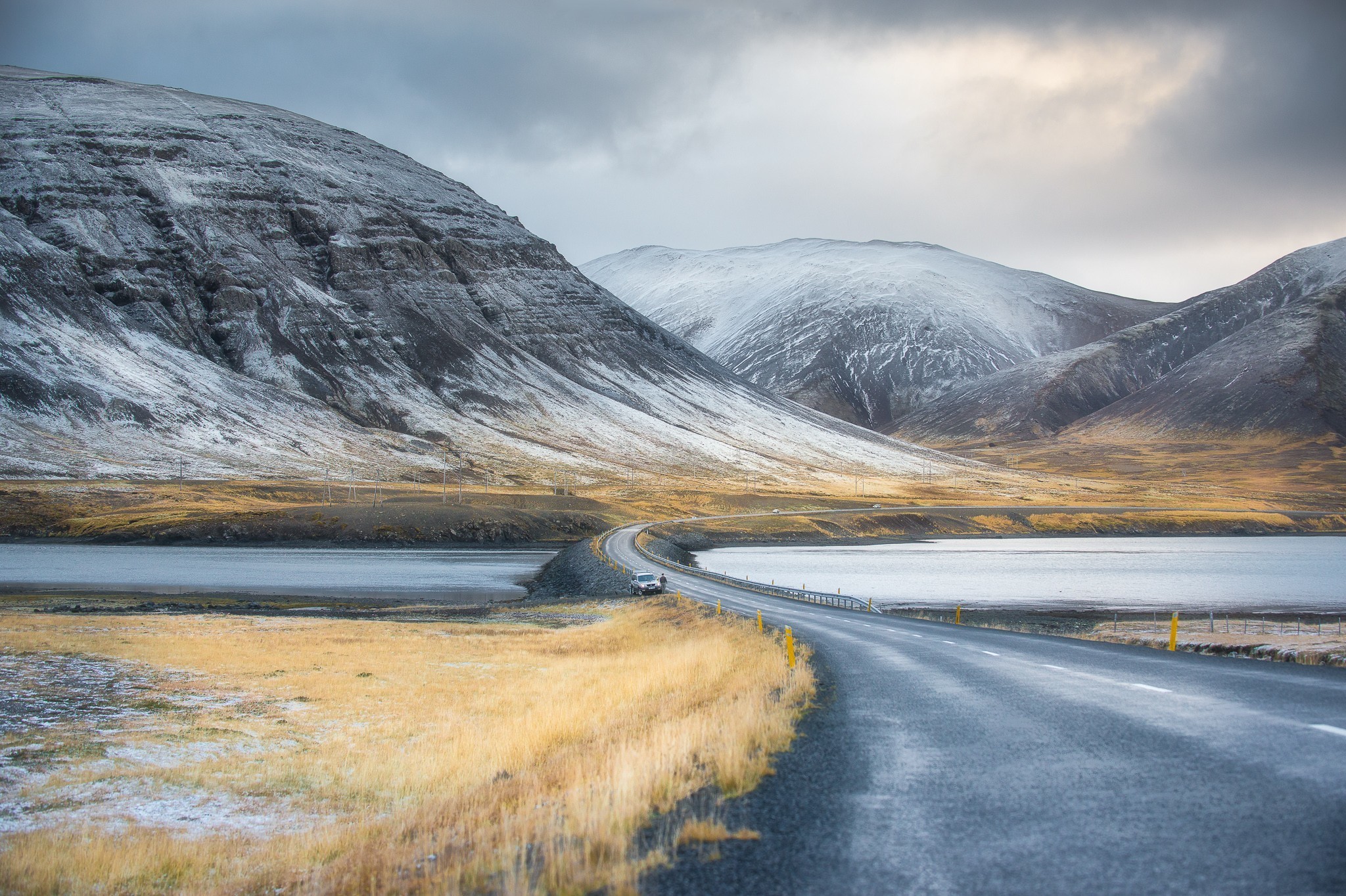 Road through snowy mountains and a lake in winter HD Wallpaper