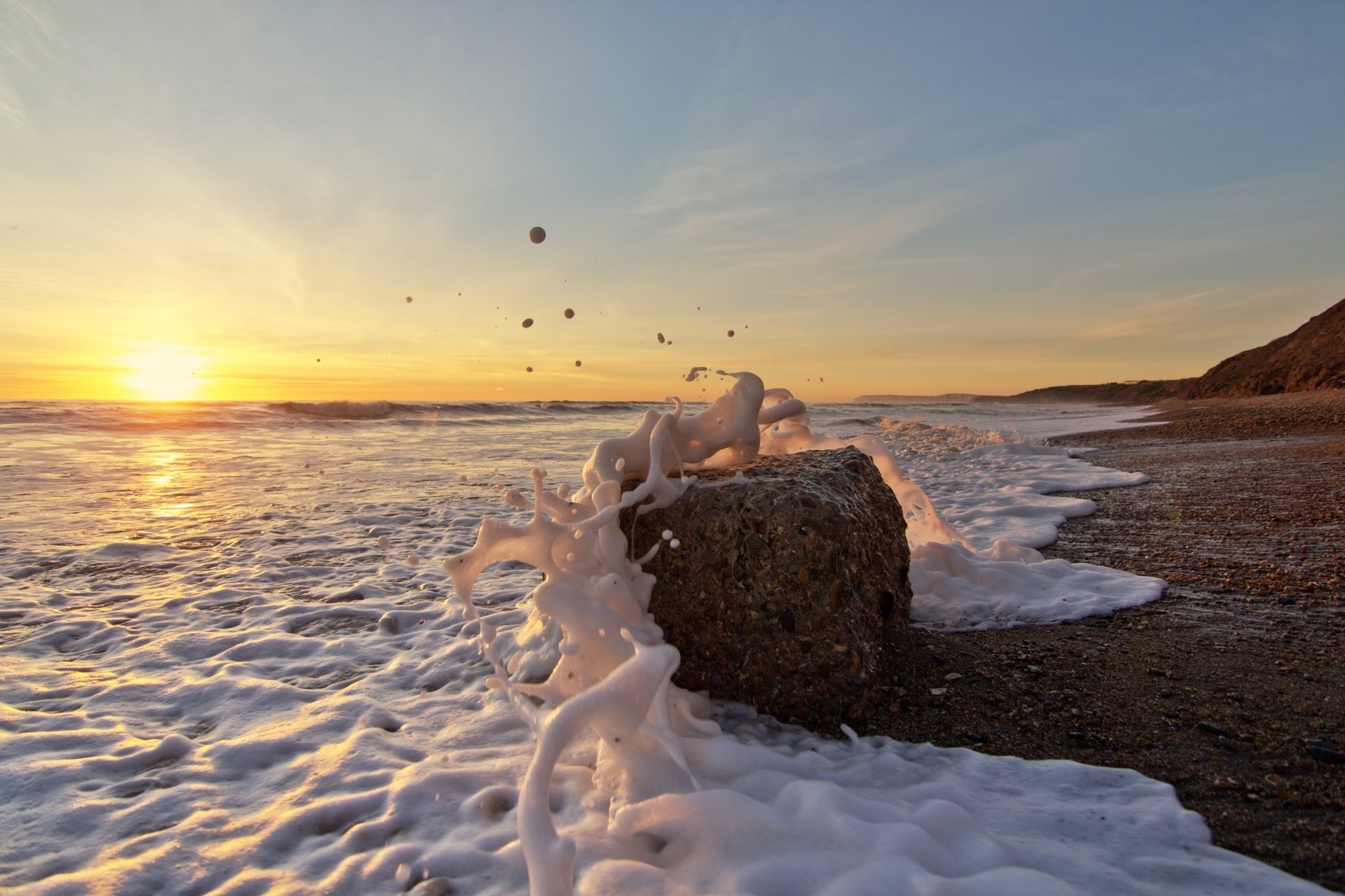 Waves crashing on a rock at sunset HD Wallpaper